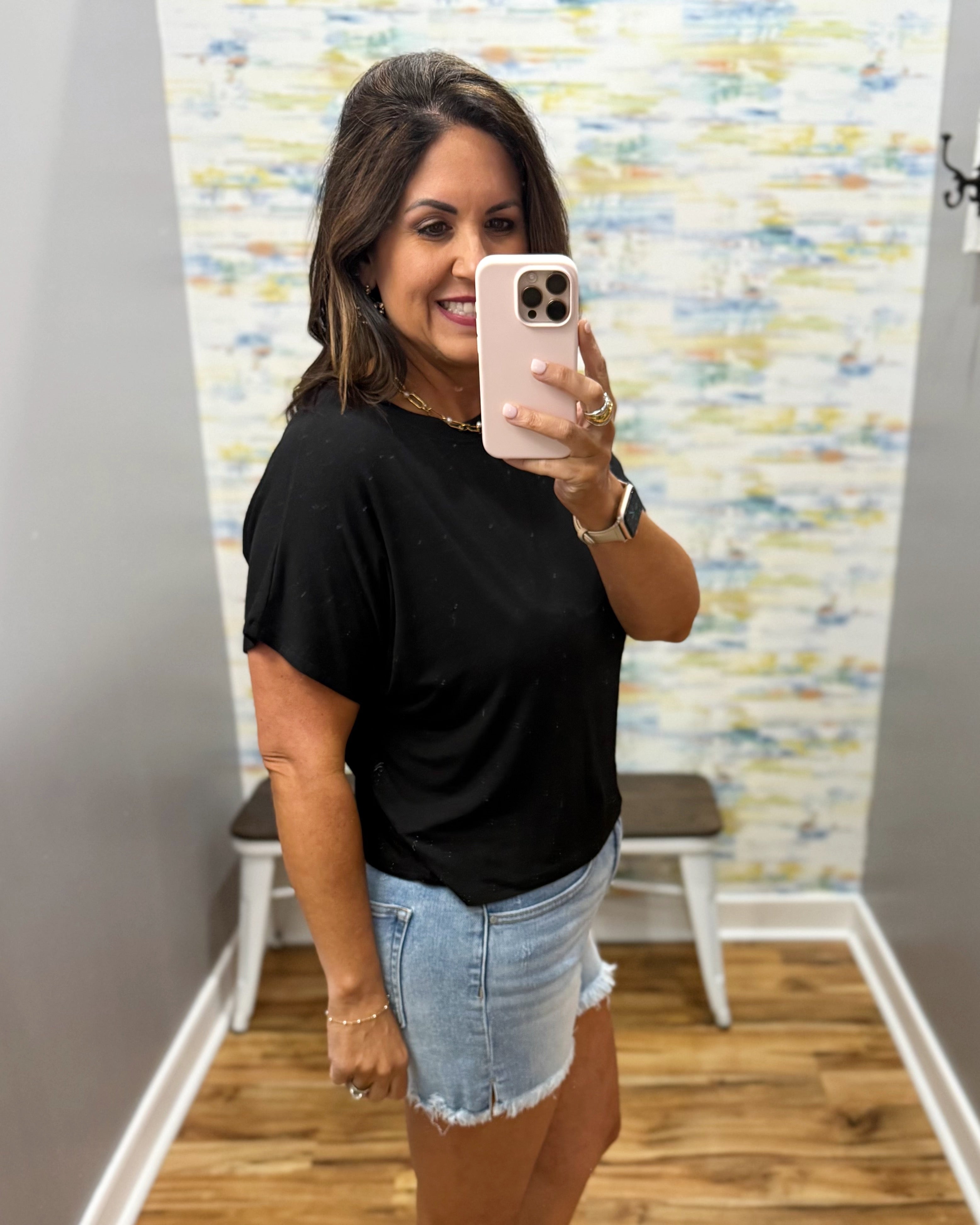 woman wearing black tee with denim shorts.