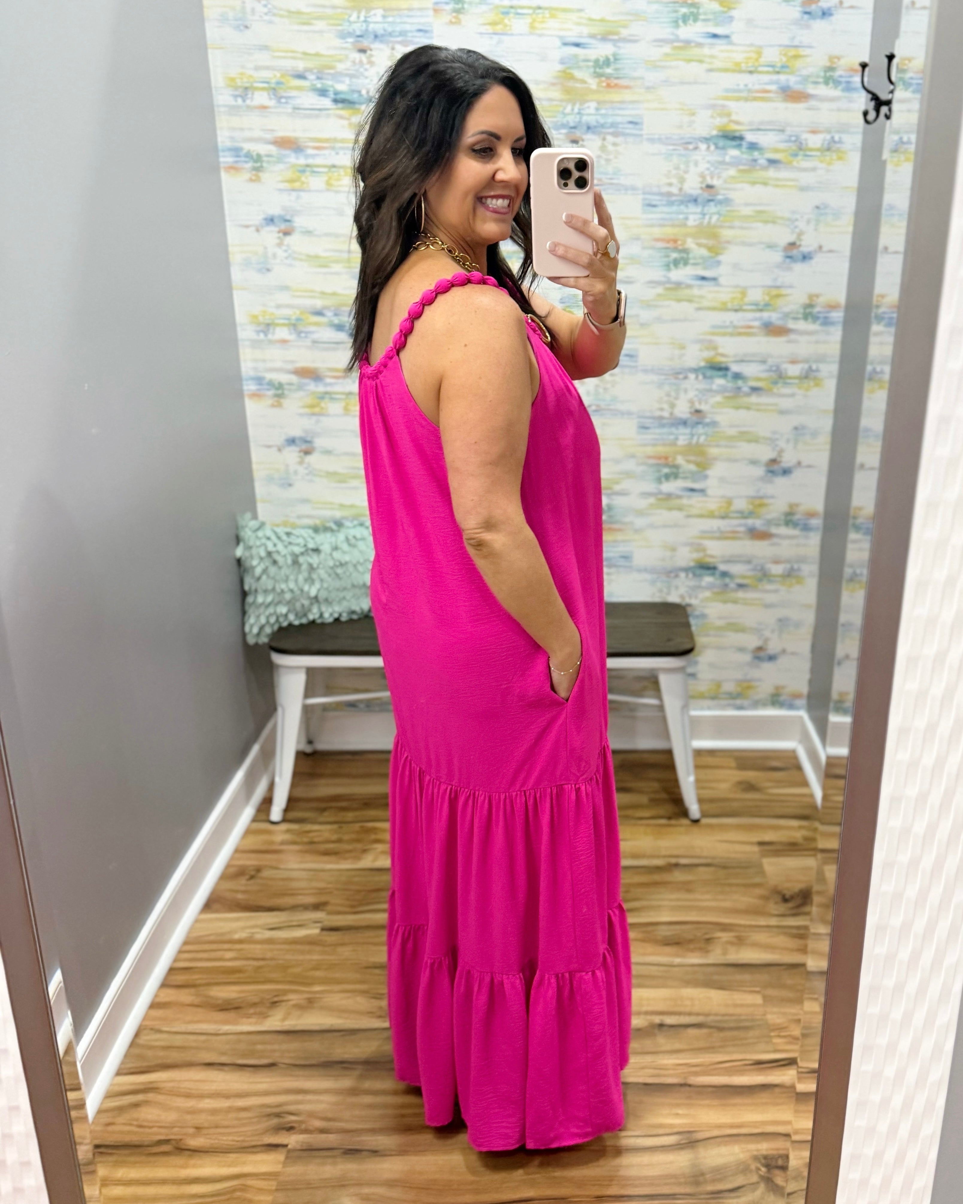 Woman wearing a pink dress taking a mirror selfie in a store.