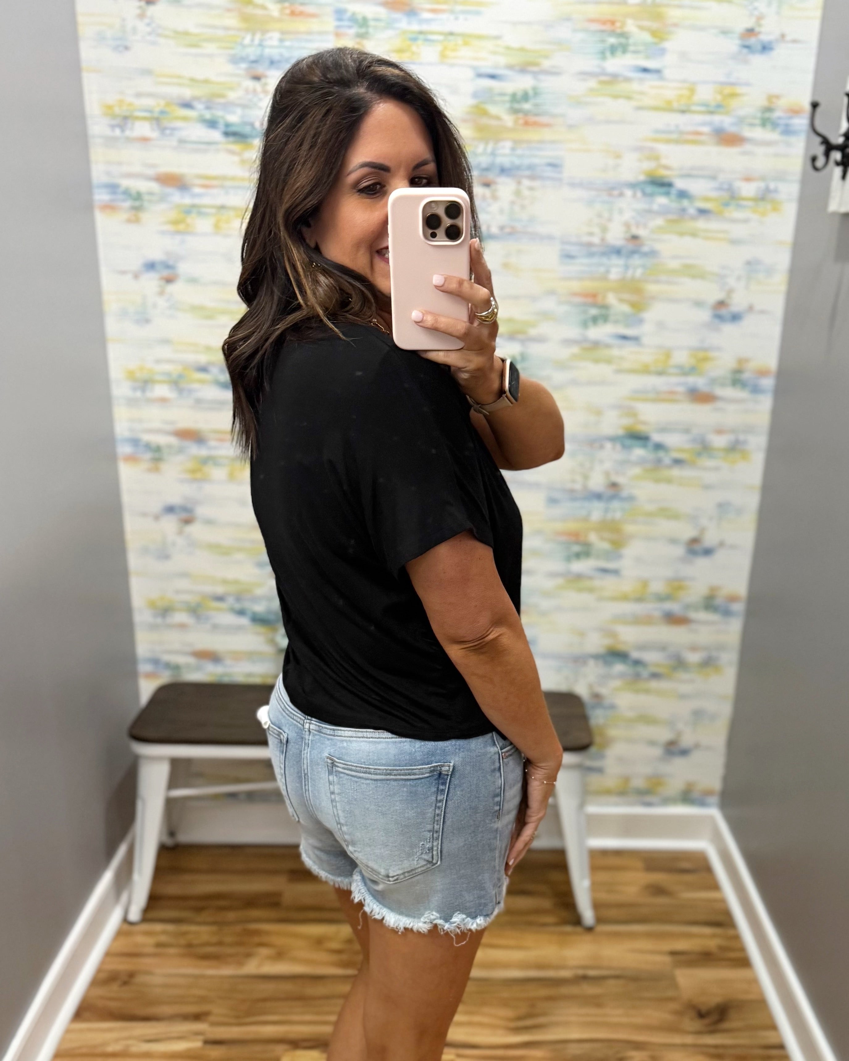 woman wearing black tee with denim shorts.