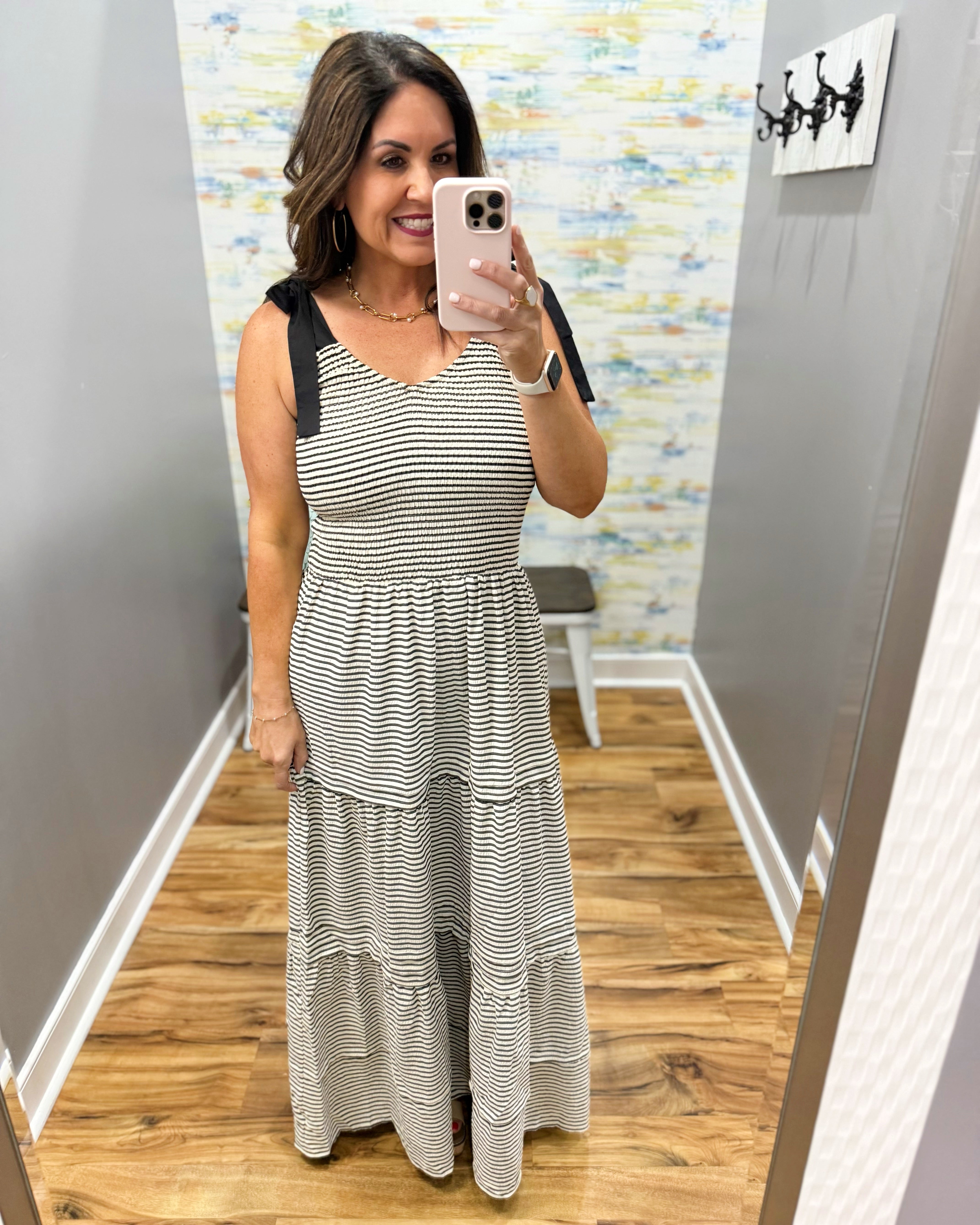 Woman taking a mirror selfie wearing a striped dress in a room with a colorful wall.