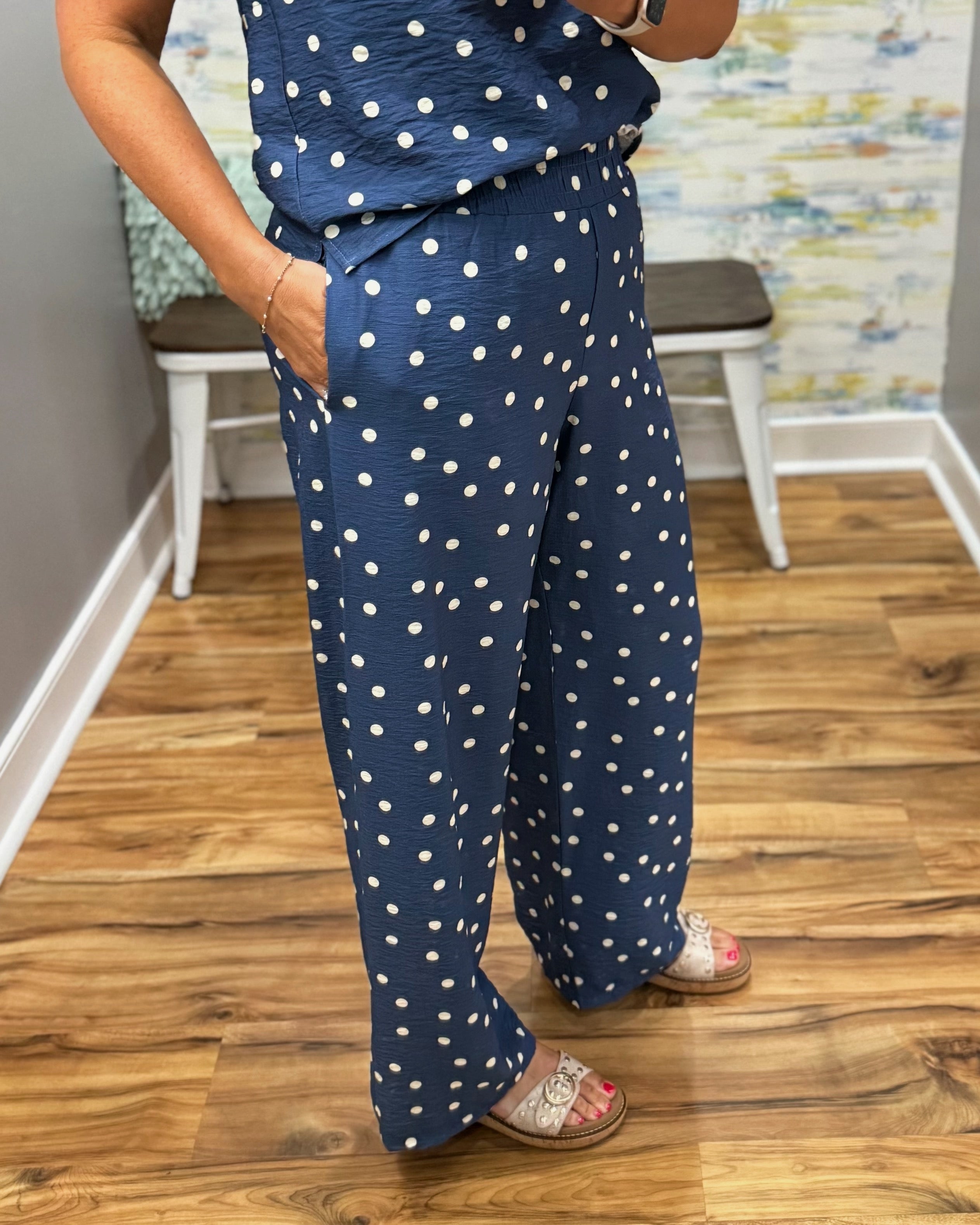 Person wearing a navy blue outfit with white polka dots on a wooden floor.