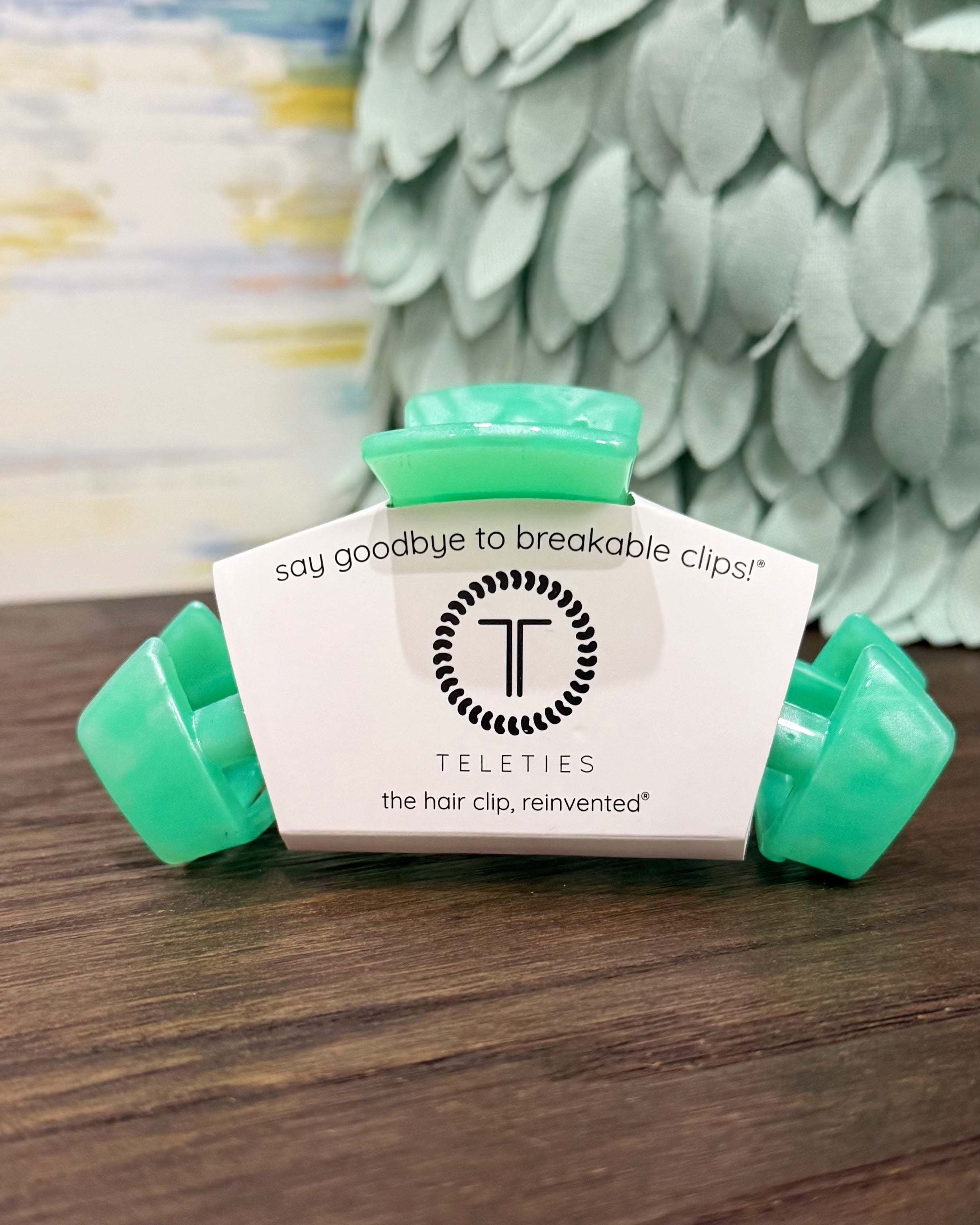 Teal hair clip with white label on a wooden surface