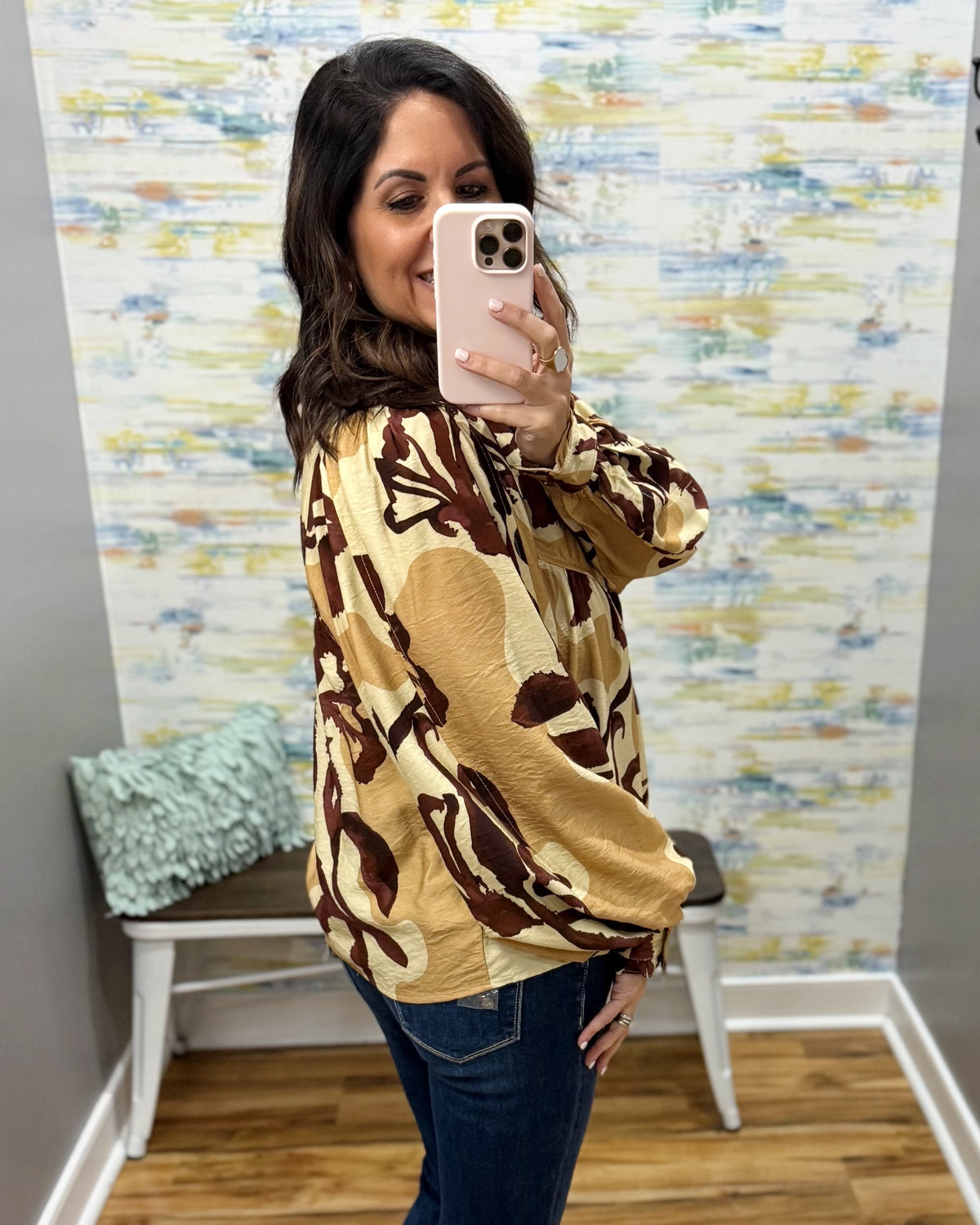 woman wearing an abstract print long sleeve top in sand, taupe, and brown.