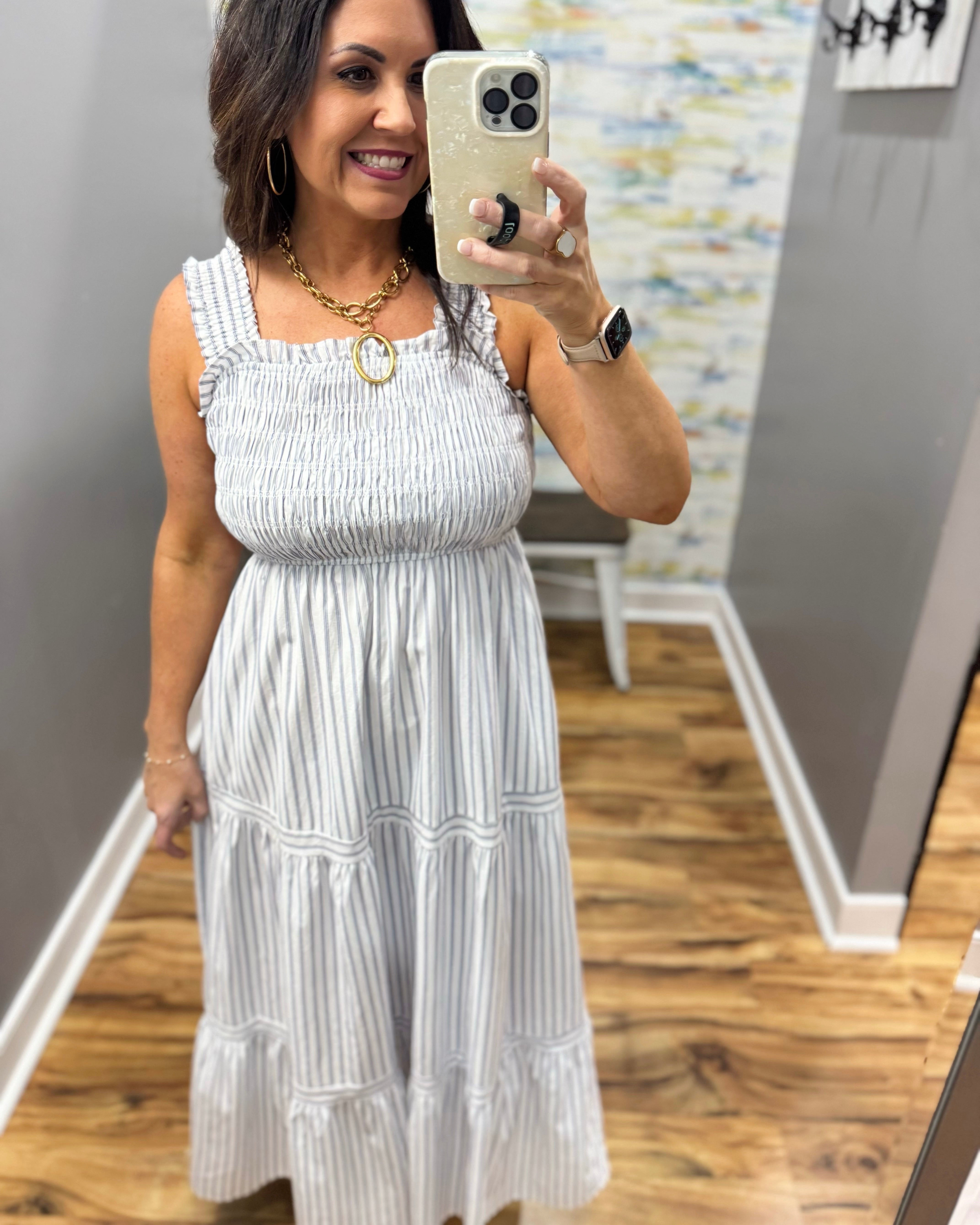 Woman wearing a white dress in a room with gray walls and wooden flooring.