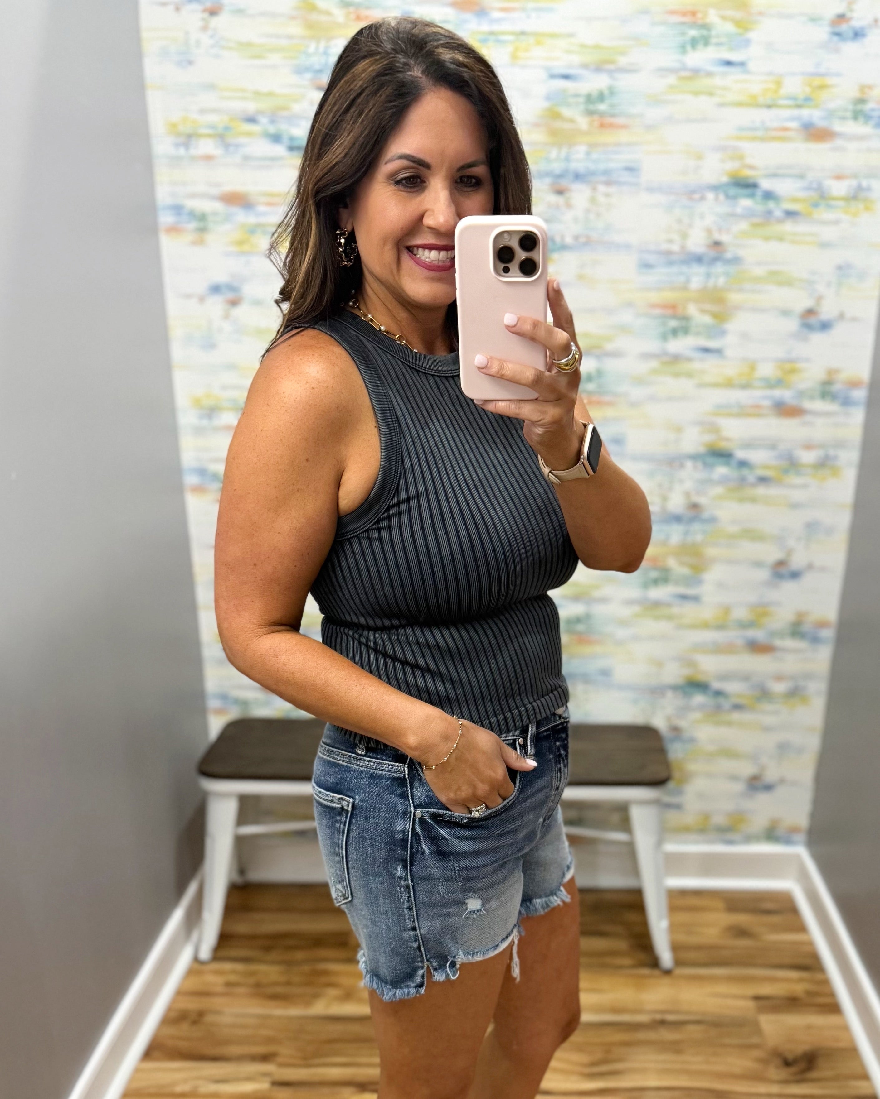 woman wearing black tank with denim shorts.