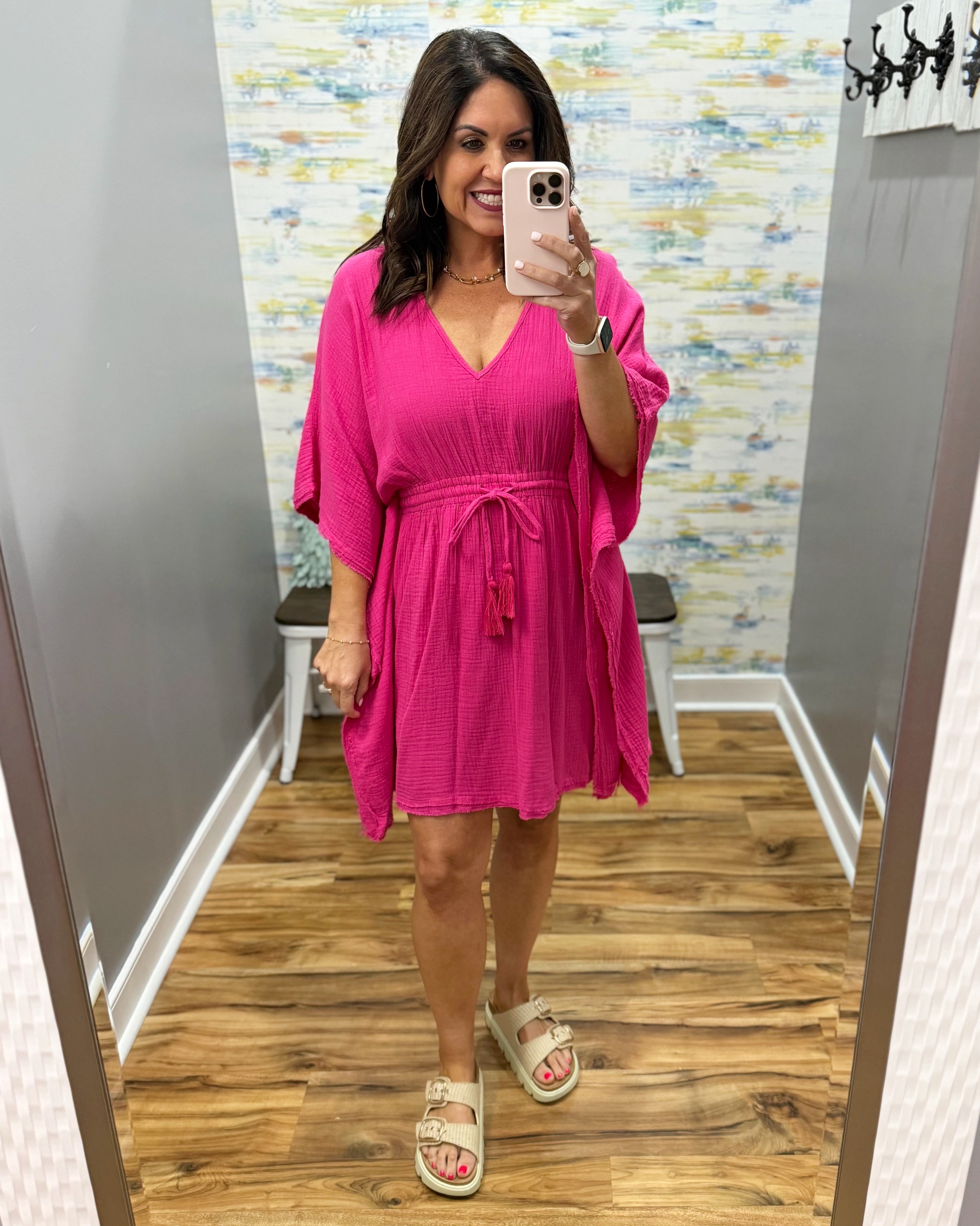 Woman wearing a pink dress in a mirror selfie setting.