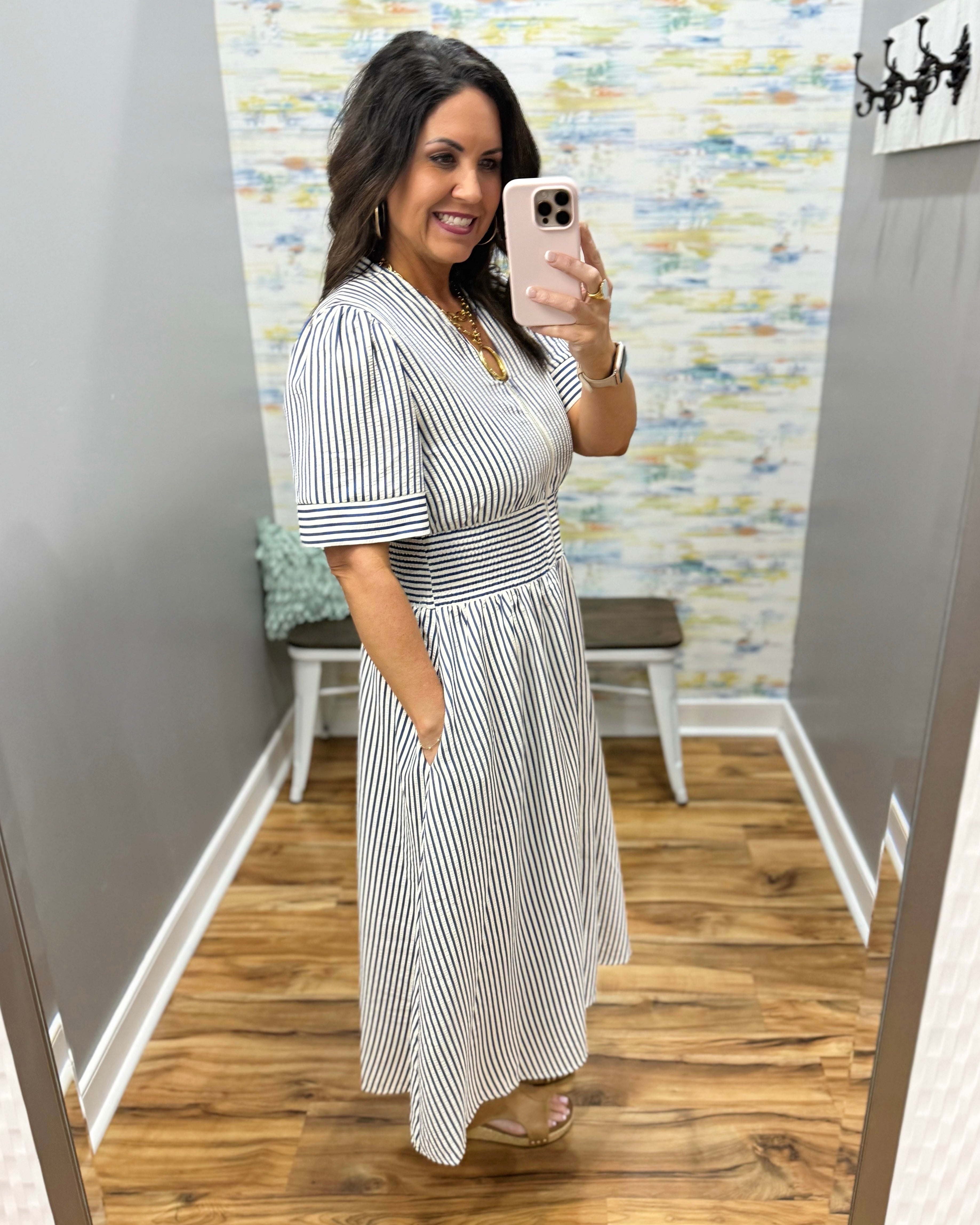 Woman wearing a striped dress in a room with a colorful wall.