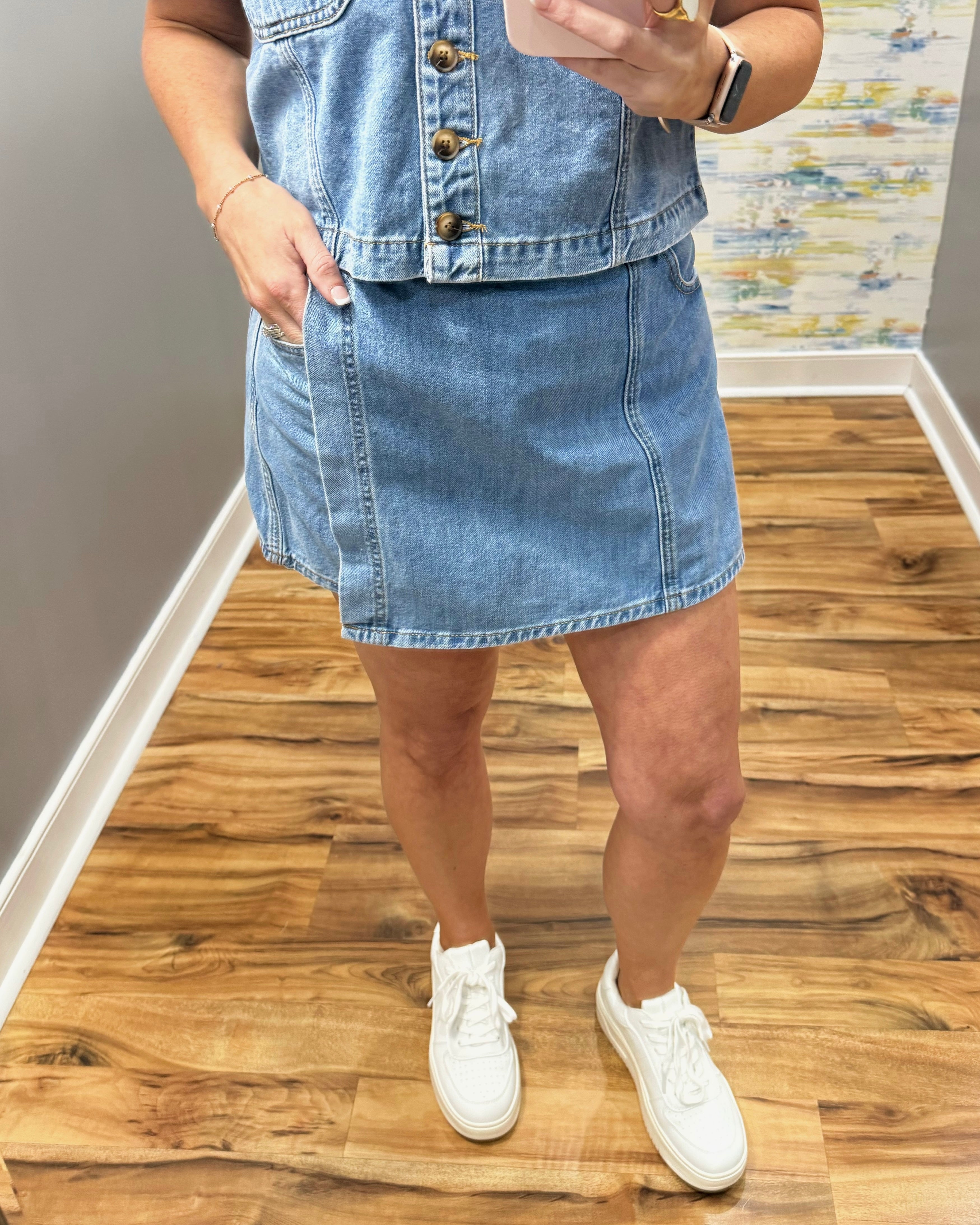woman wearing denim skort with white sneakers.