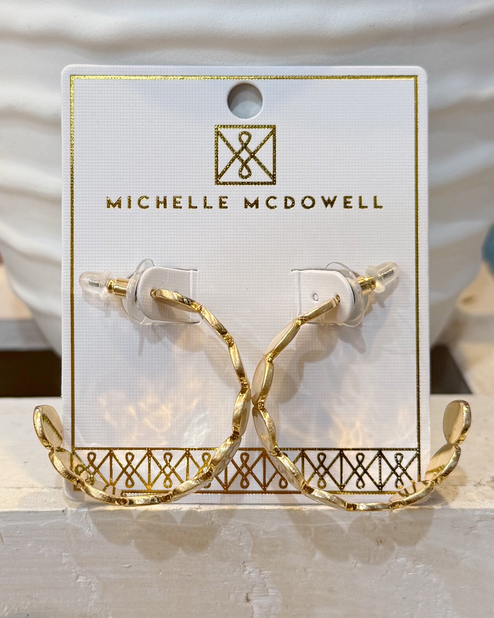 Gold hoop earrings on a branded card with 'Michelle McDowell' on a neutral background