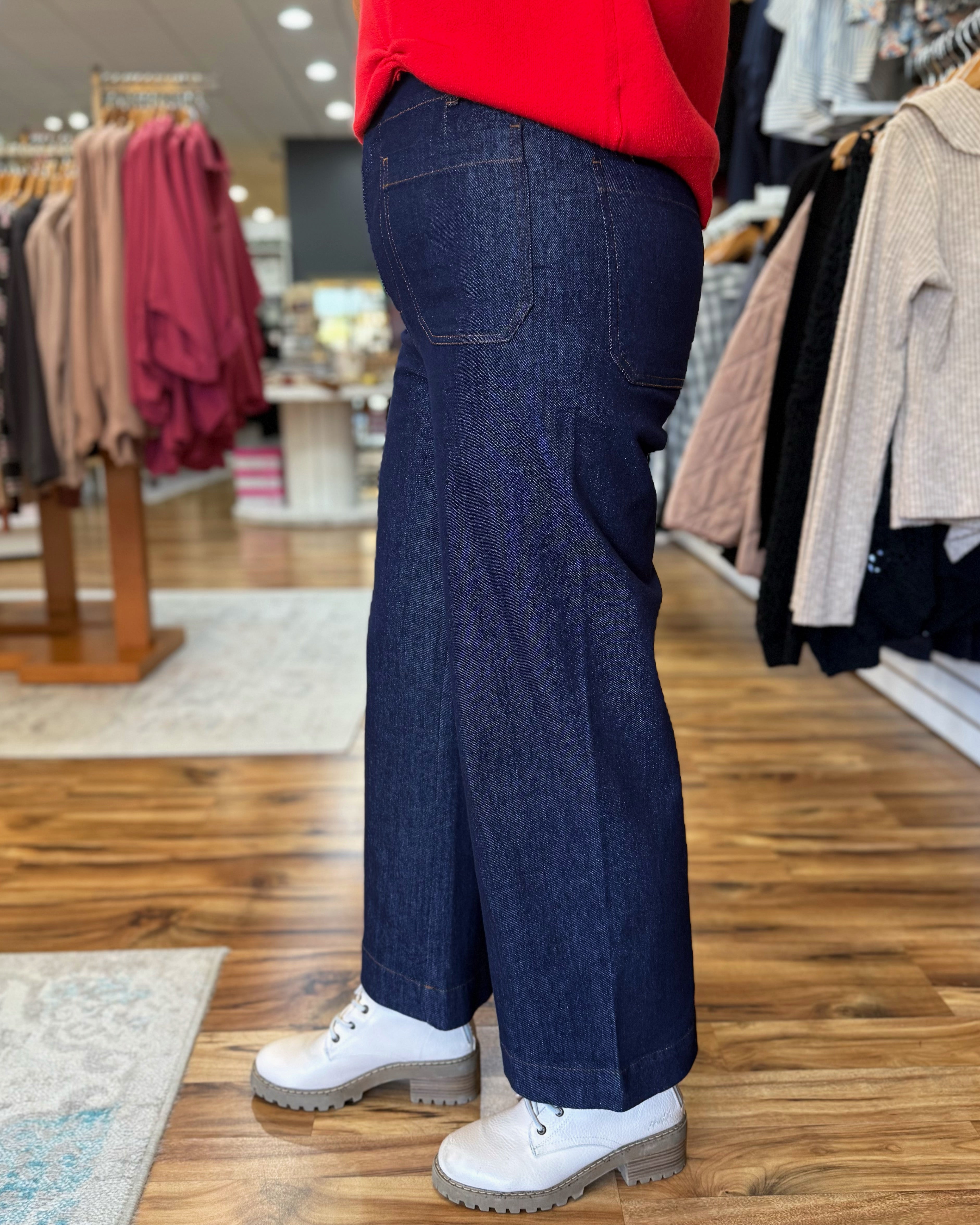 Person wearing blue jeans and a red sweater in a clothing store.