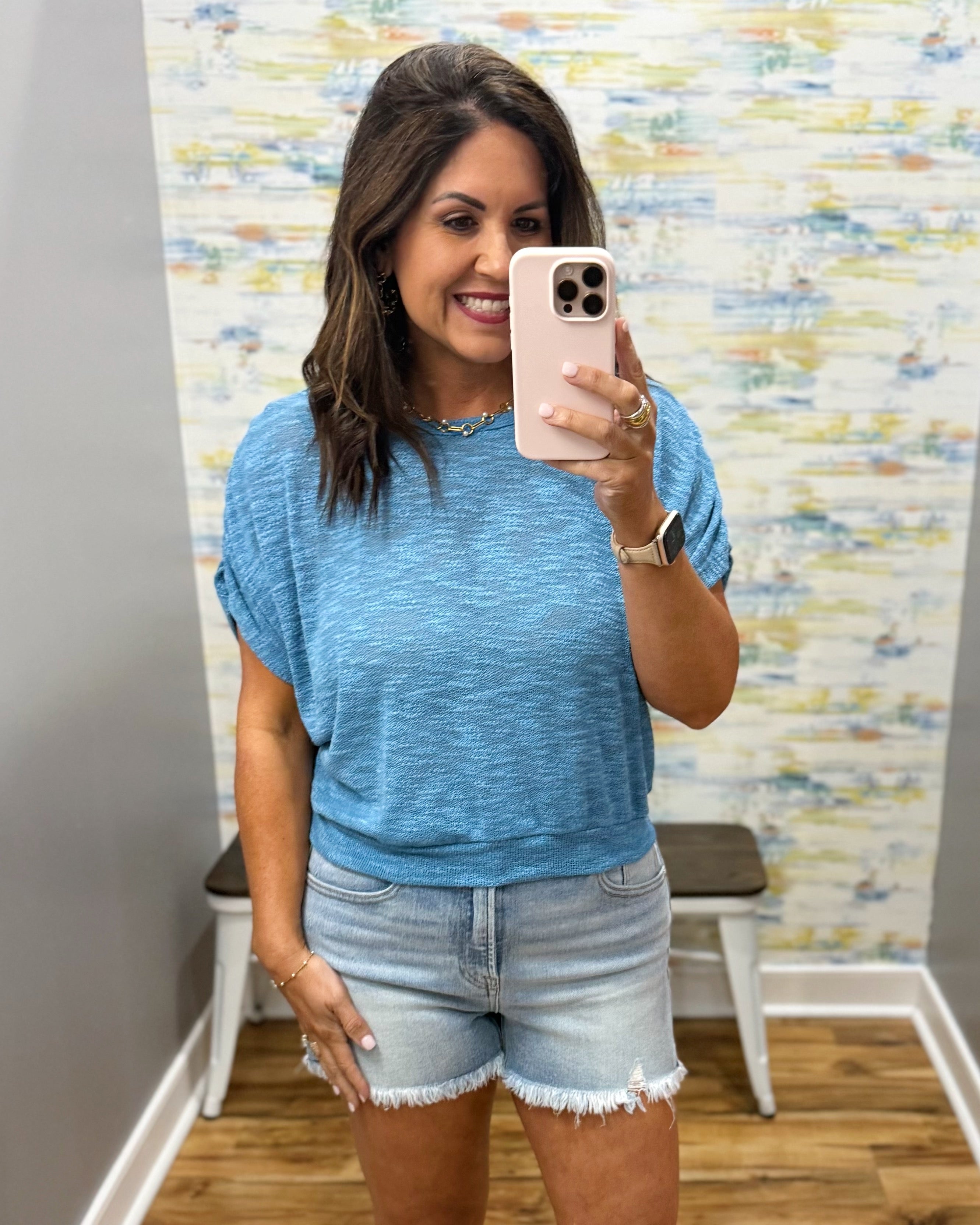 woman wearing a blue top with denim shorts.