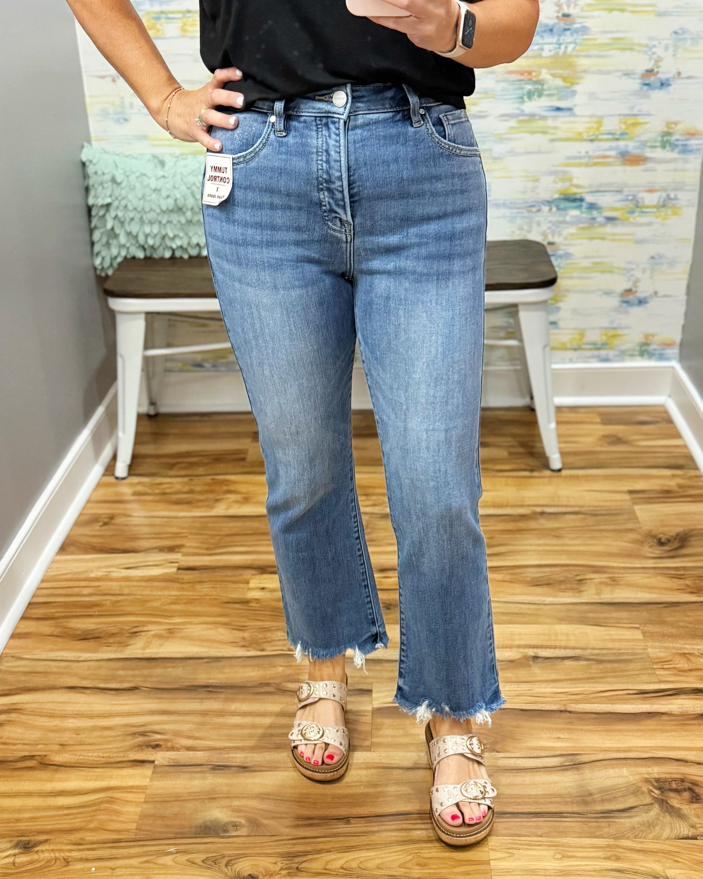 Person wearing blue jeans with a visible brand tag, standing on a wooden floor.