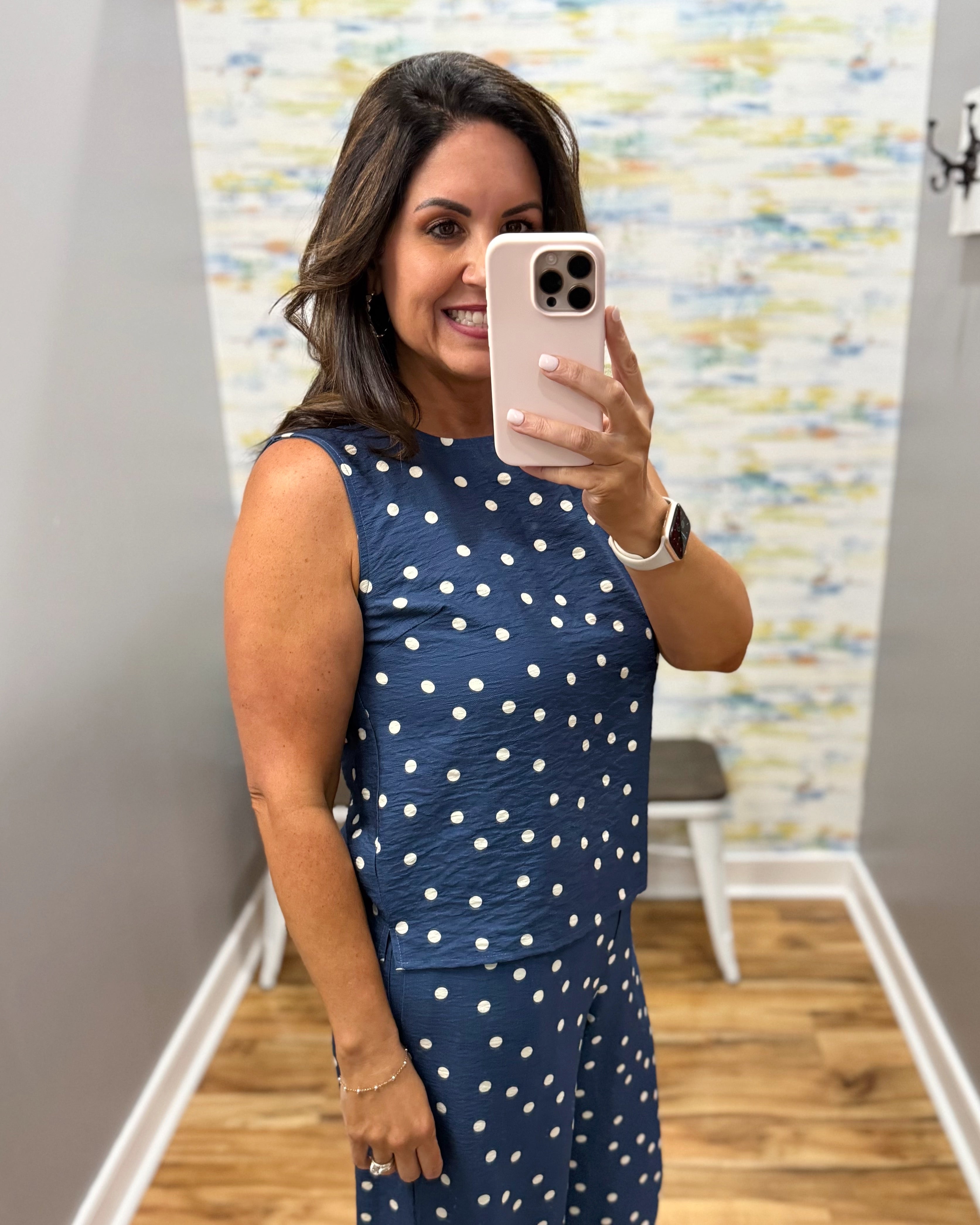 Woman taking a mirror selfie wearing a navy blue dress with white polka dots.