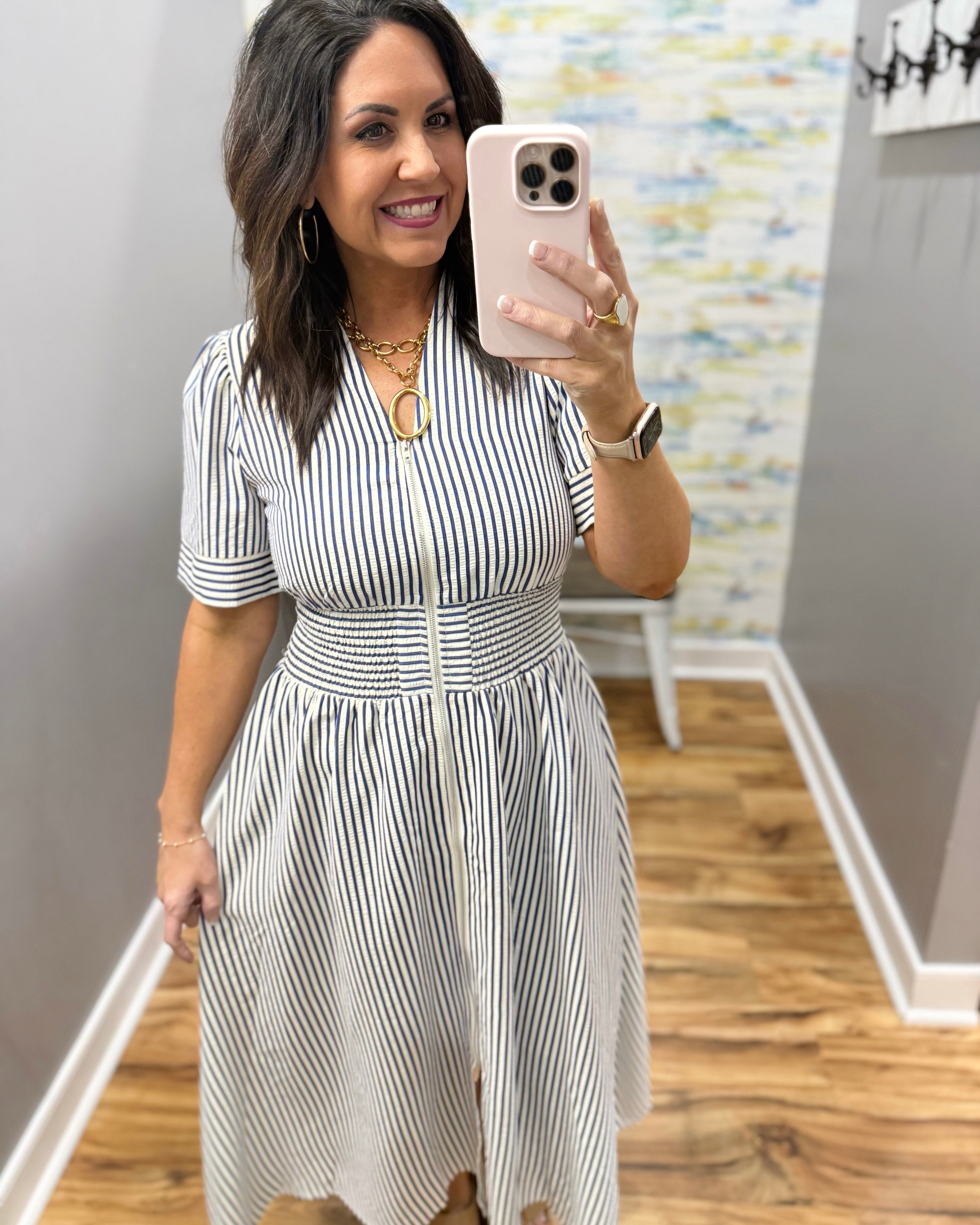 Woman wearing a striped dress in a room with a colorful wall.