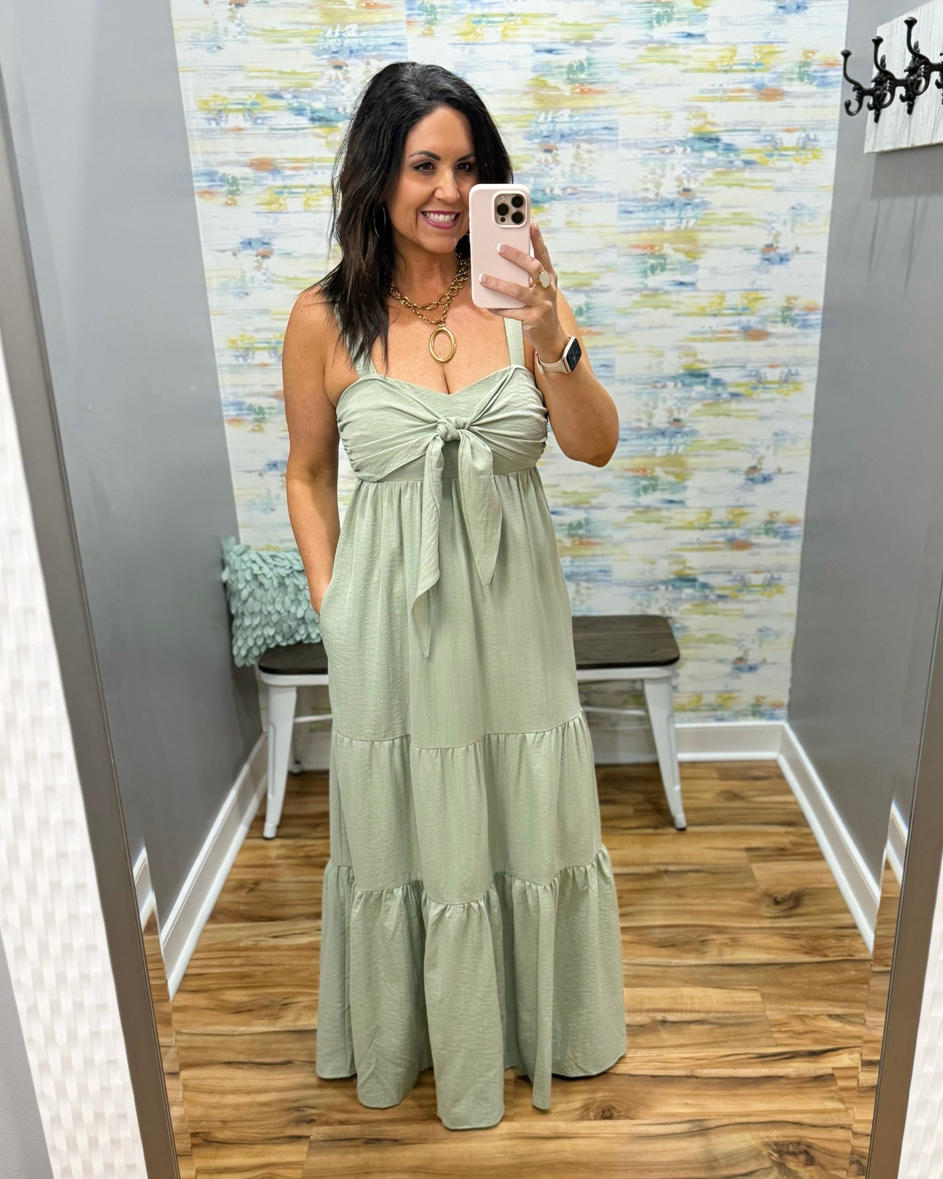 Woman wearing a green dress in a room with patterned wallpaper.