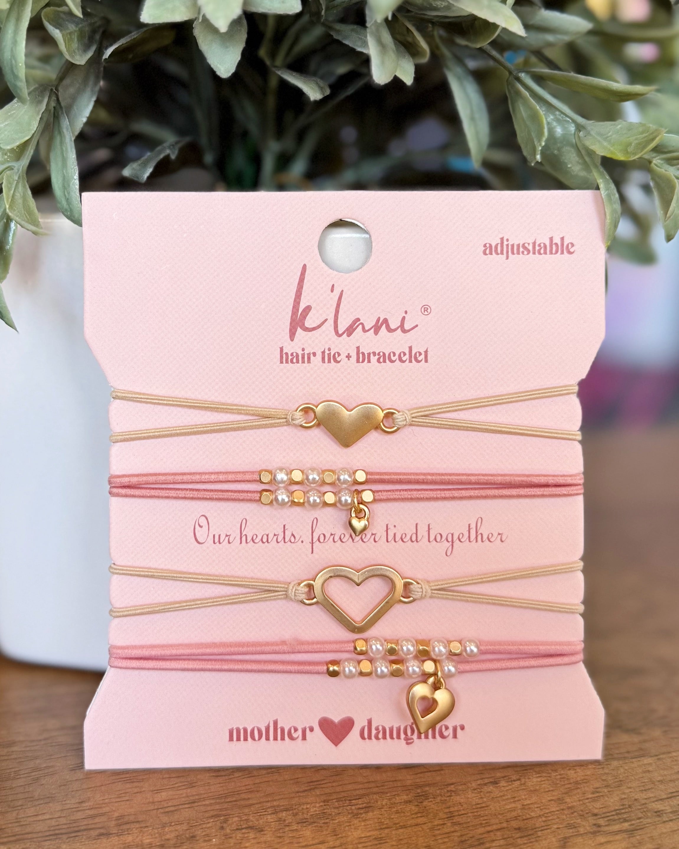 Kilani hair tie and bracelet set on a pink card with decorative elements.