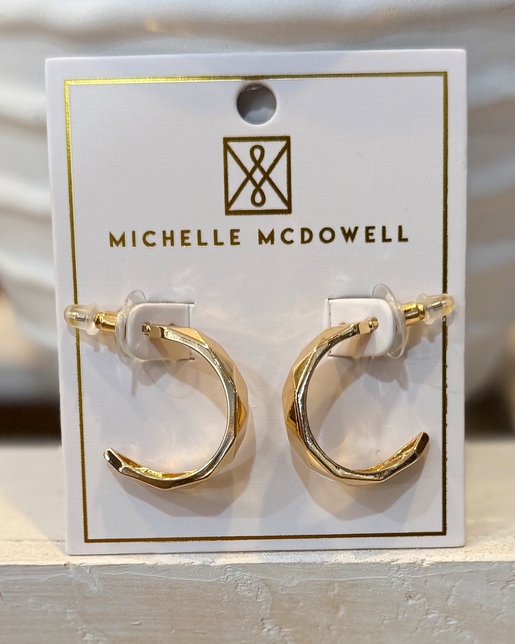 Gold hoop earrings on a Michelle McDowell branded card.