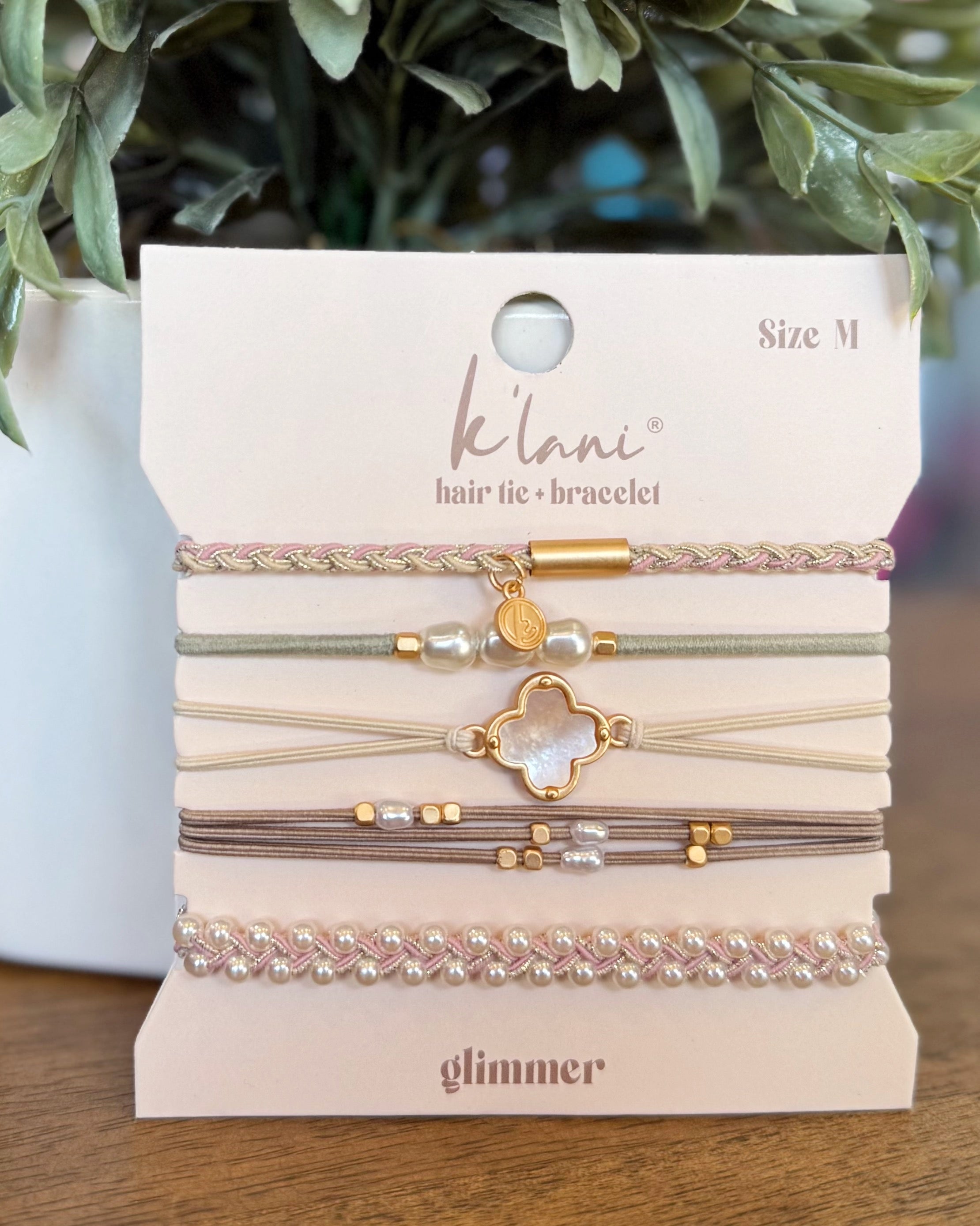 Set of hair ties and bracelets on a 'kilani' branded card with greenery in the background.