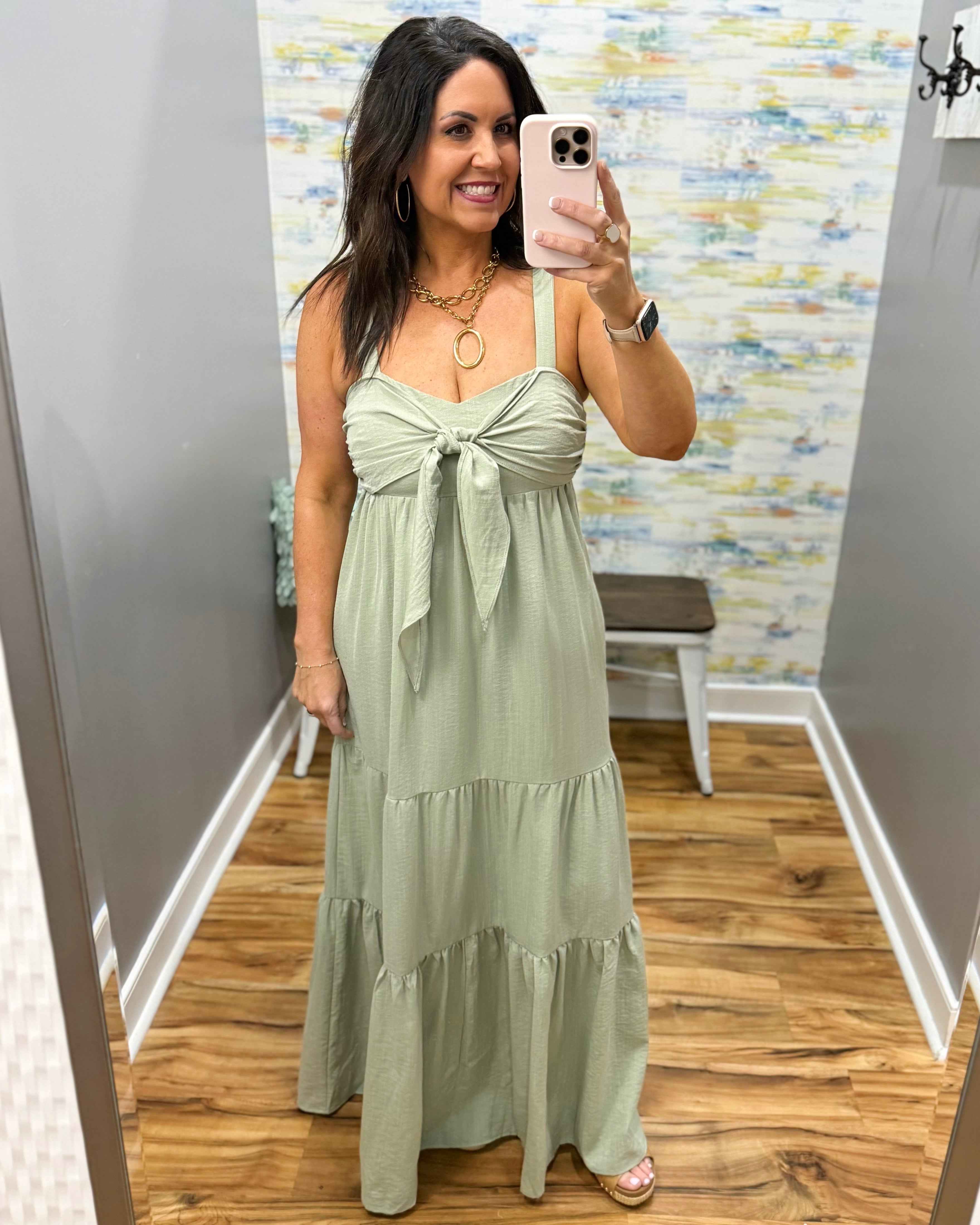 Woman wearing a green dress in a room with a patterned wall.