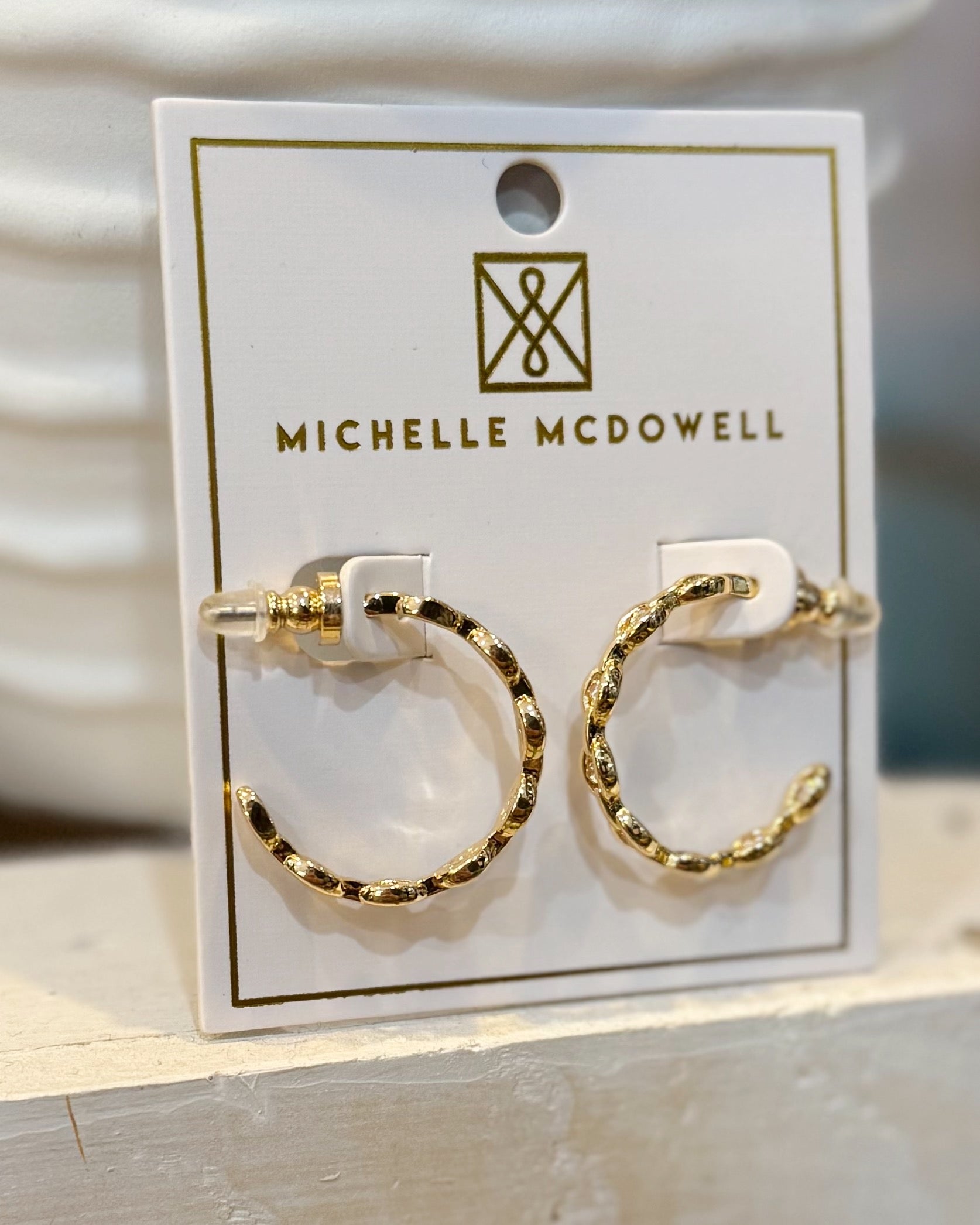 Gold hoop earrings on a Michelle McDowell branded card.