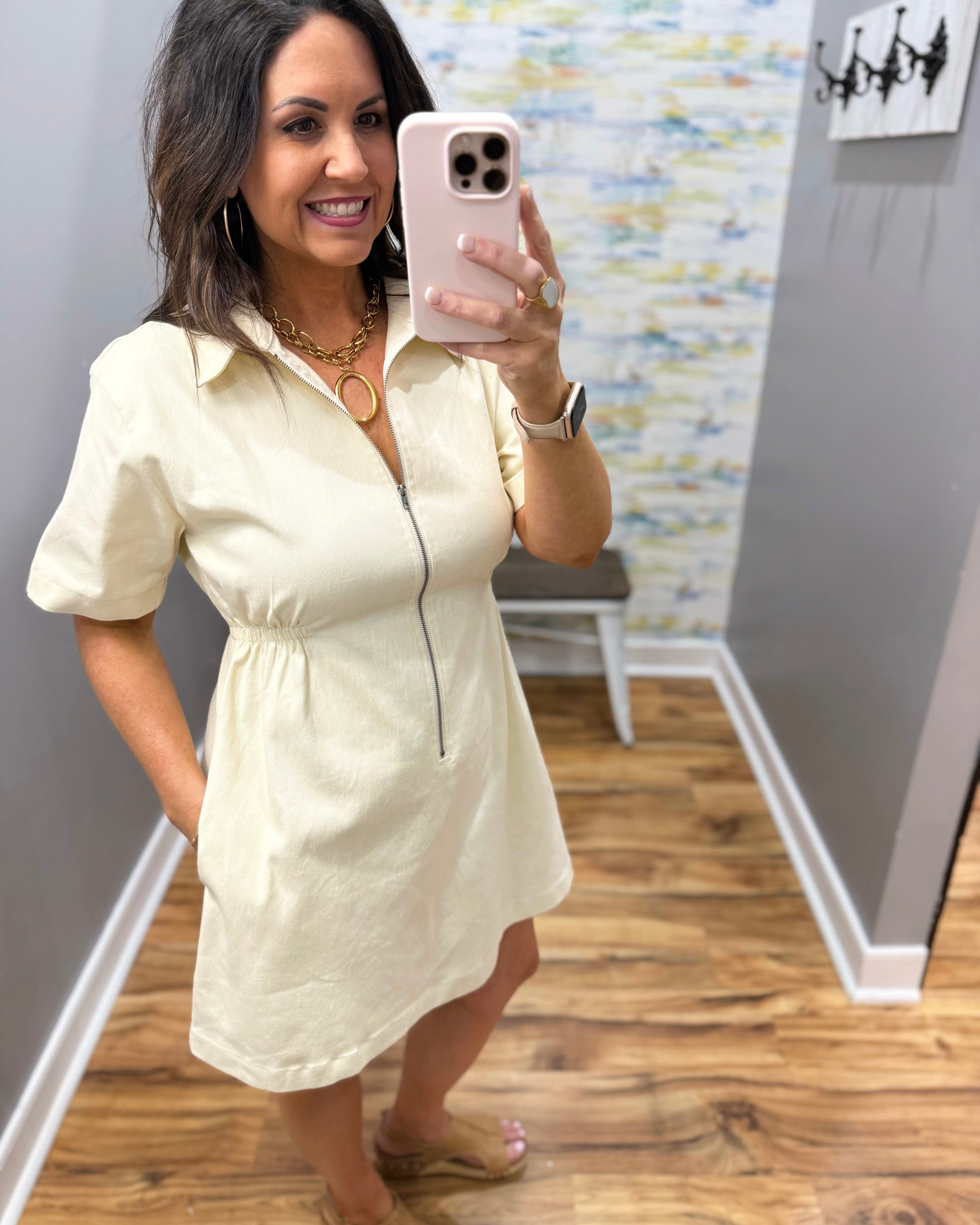 Woman wearing a light-colored dress in a room with a textured wall.