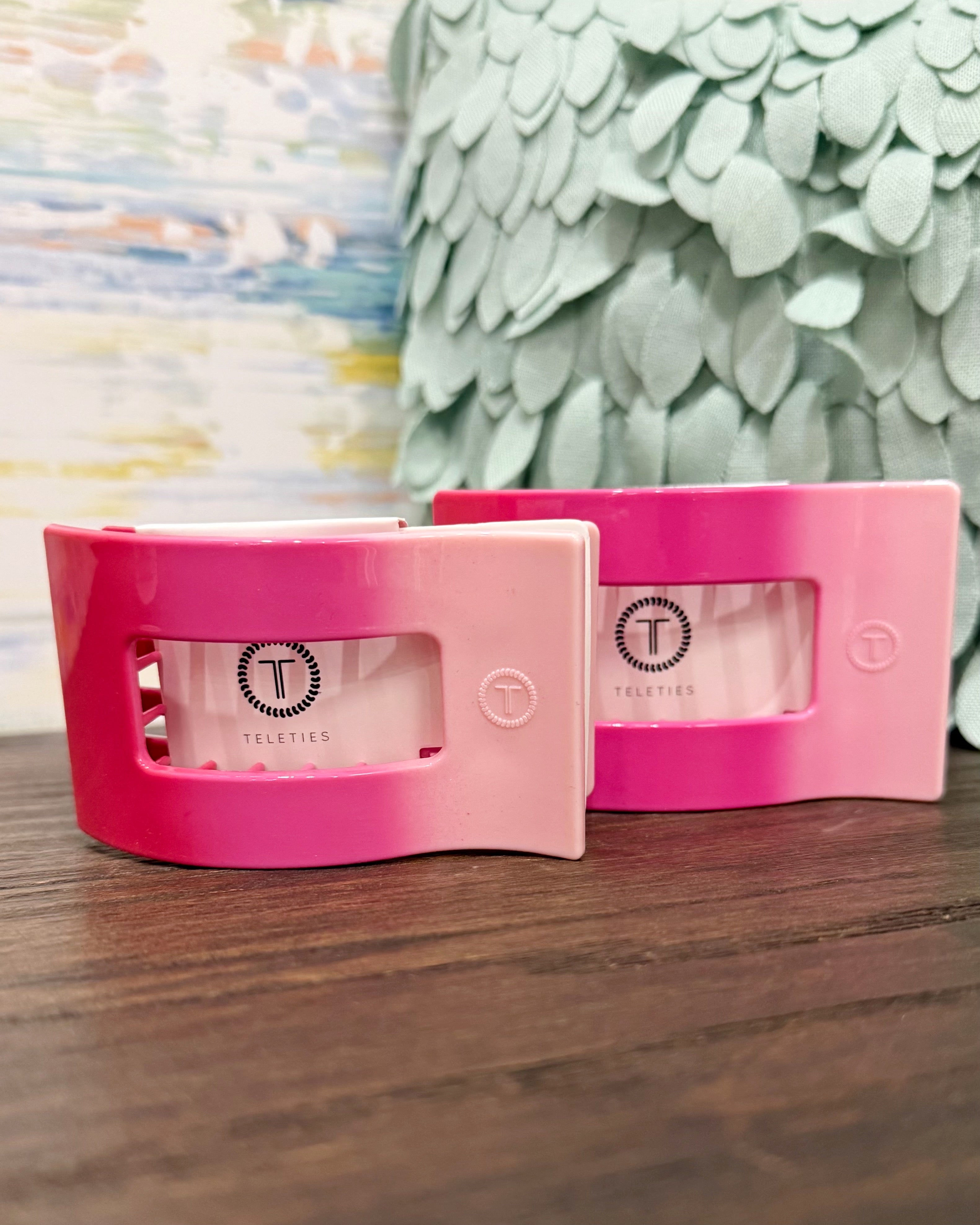 Pink and white product packaging on a wooden surface with a decorative background