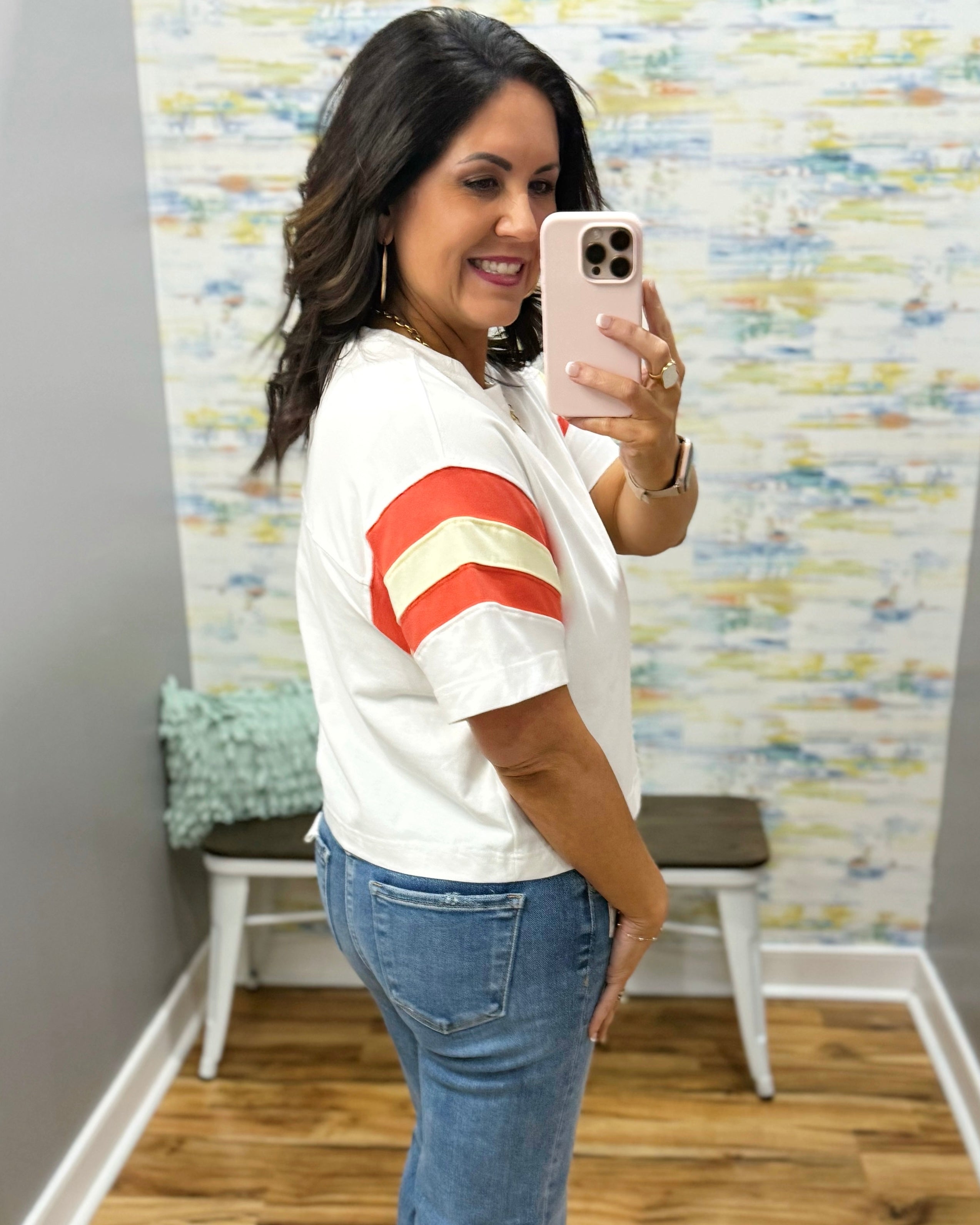 woman wearing white tee with colorful sleeves and chunky gold necklace