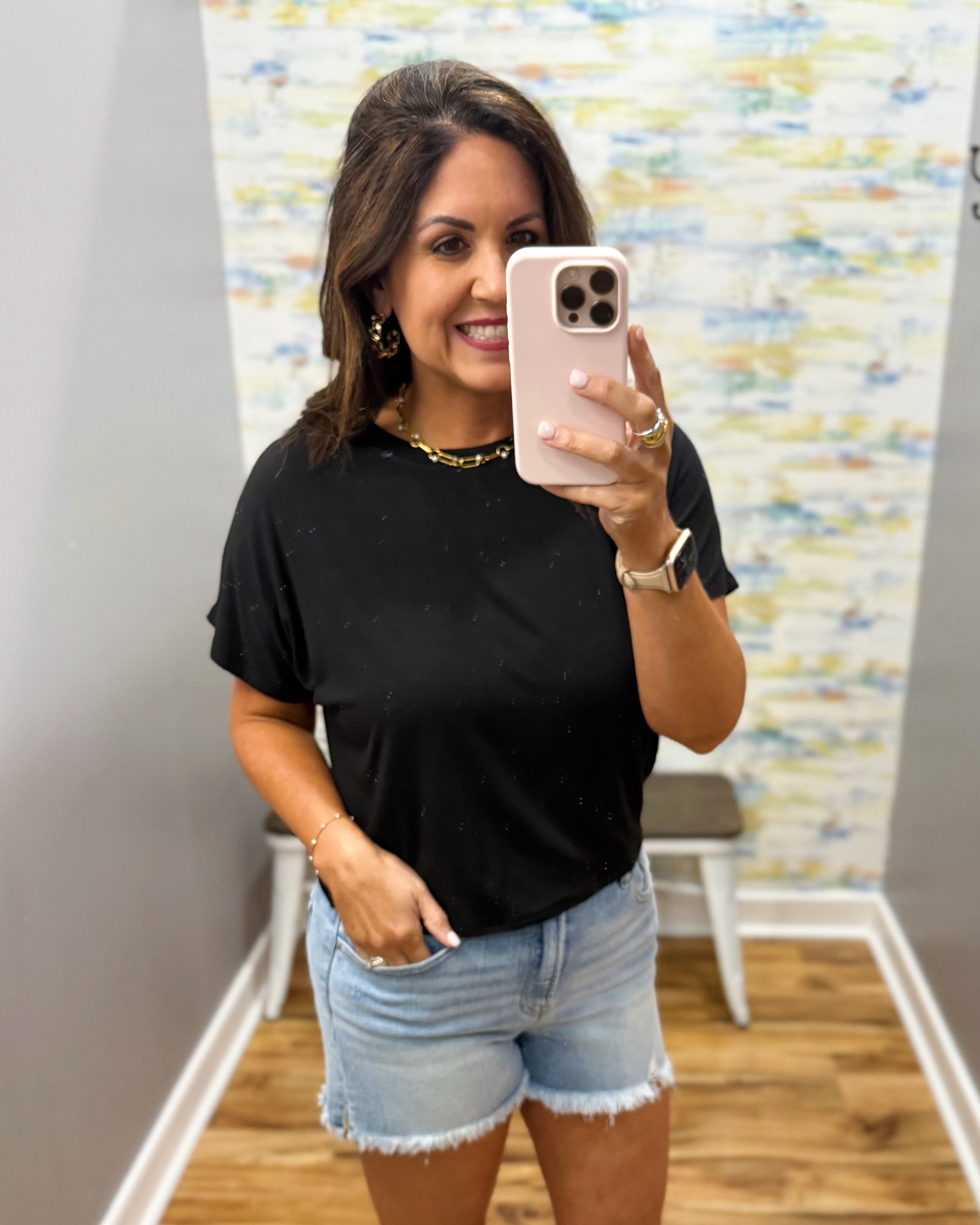 woman wearing black tee with denim shorts.