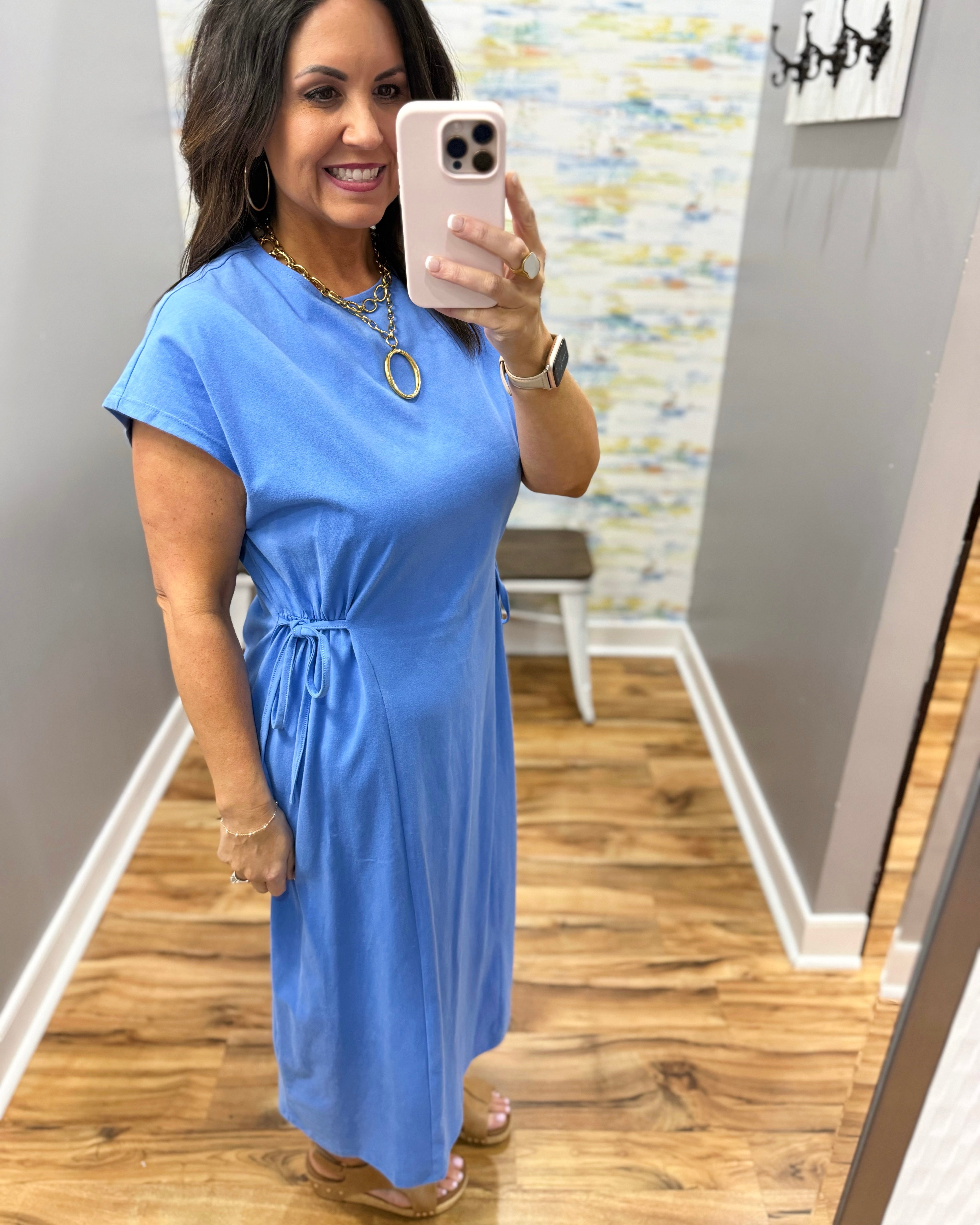Woman wearing a blue dress in a room with a patterned wall.