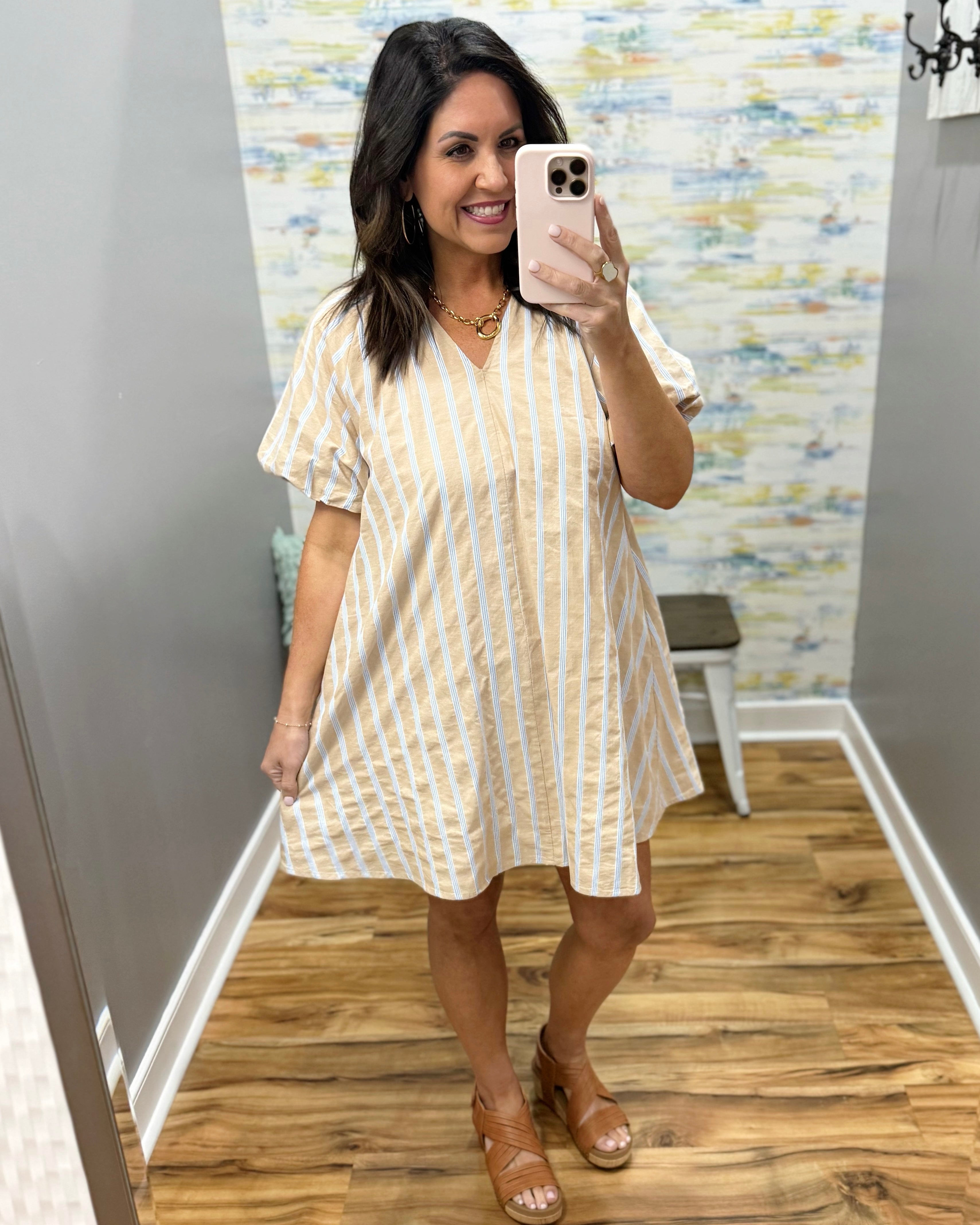Woman taking a mirror selfie wearing a natural and white striped dress.