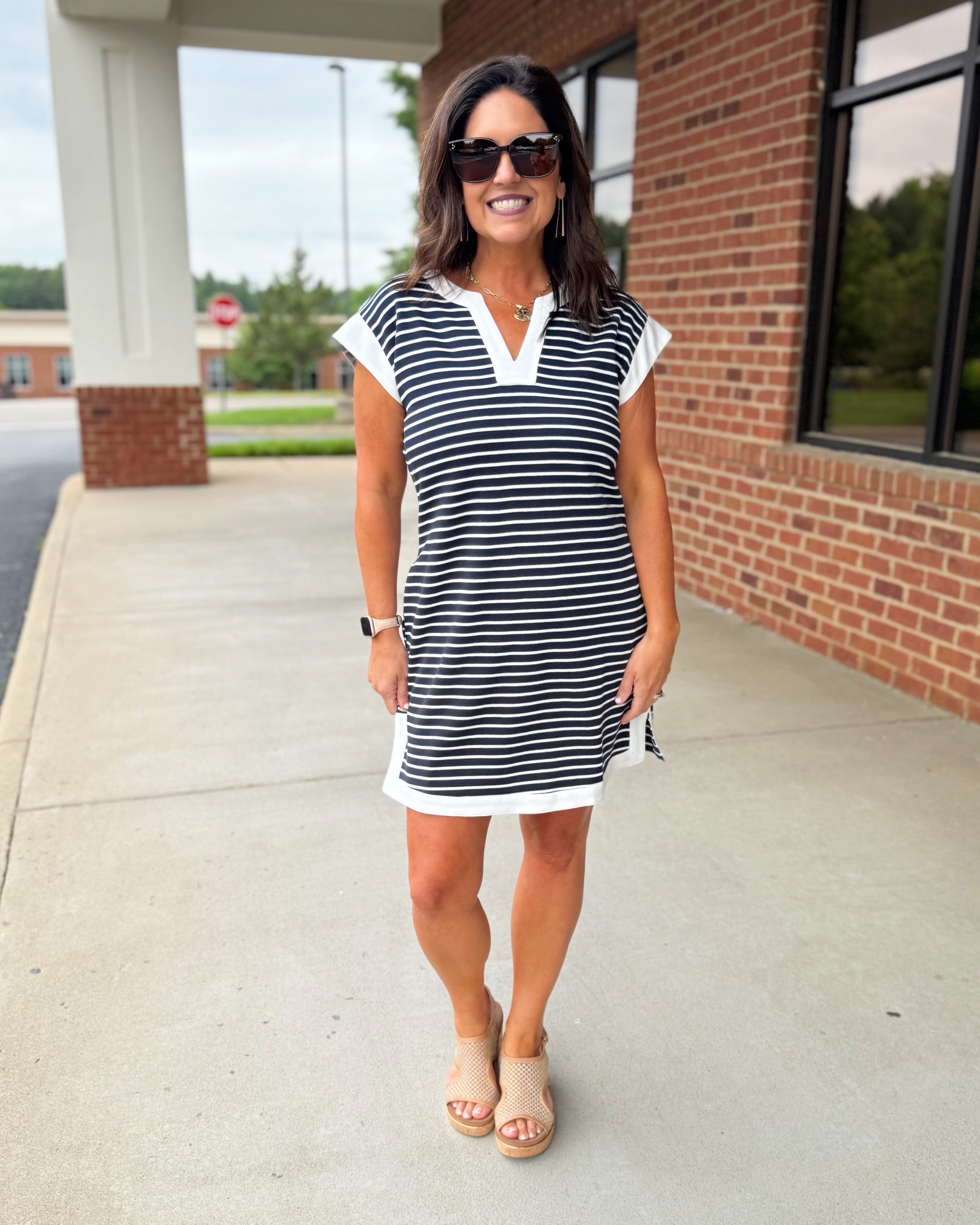 Woman wearing a navy and white striped dress standing outside a building.