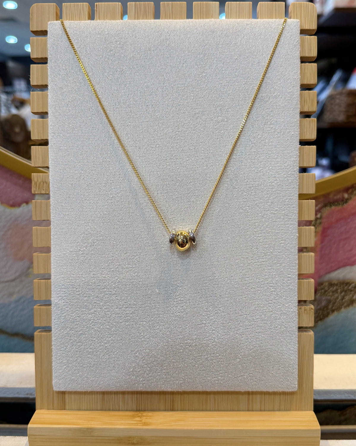 This dainty snake chain necklace features a slim polished chain with two small rounded bead sliders that sit together at the center in two tone finish.