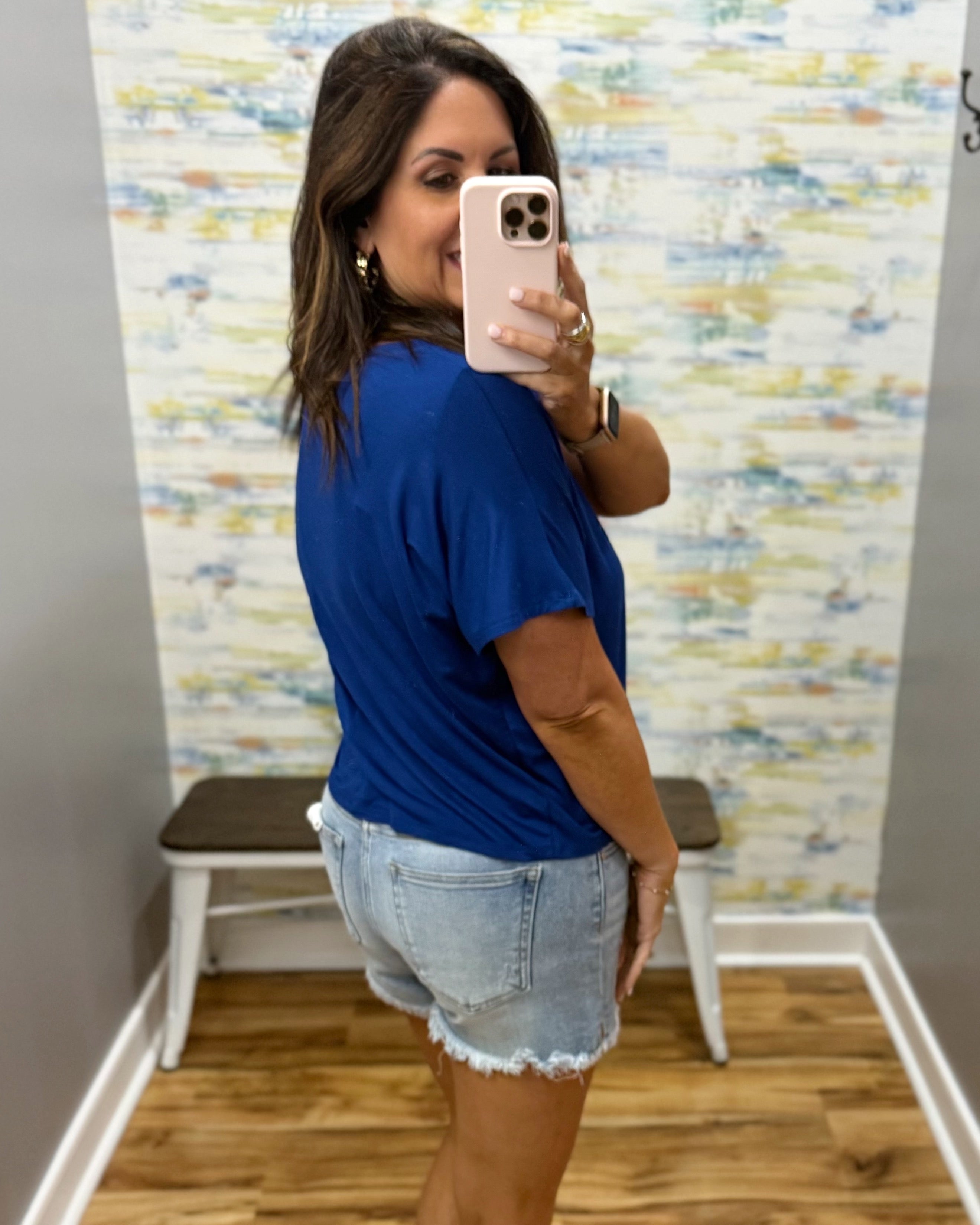 woman wearing blue t-shirt top with denim shorts.