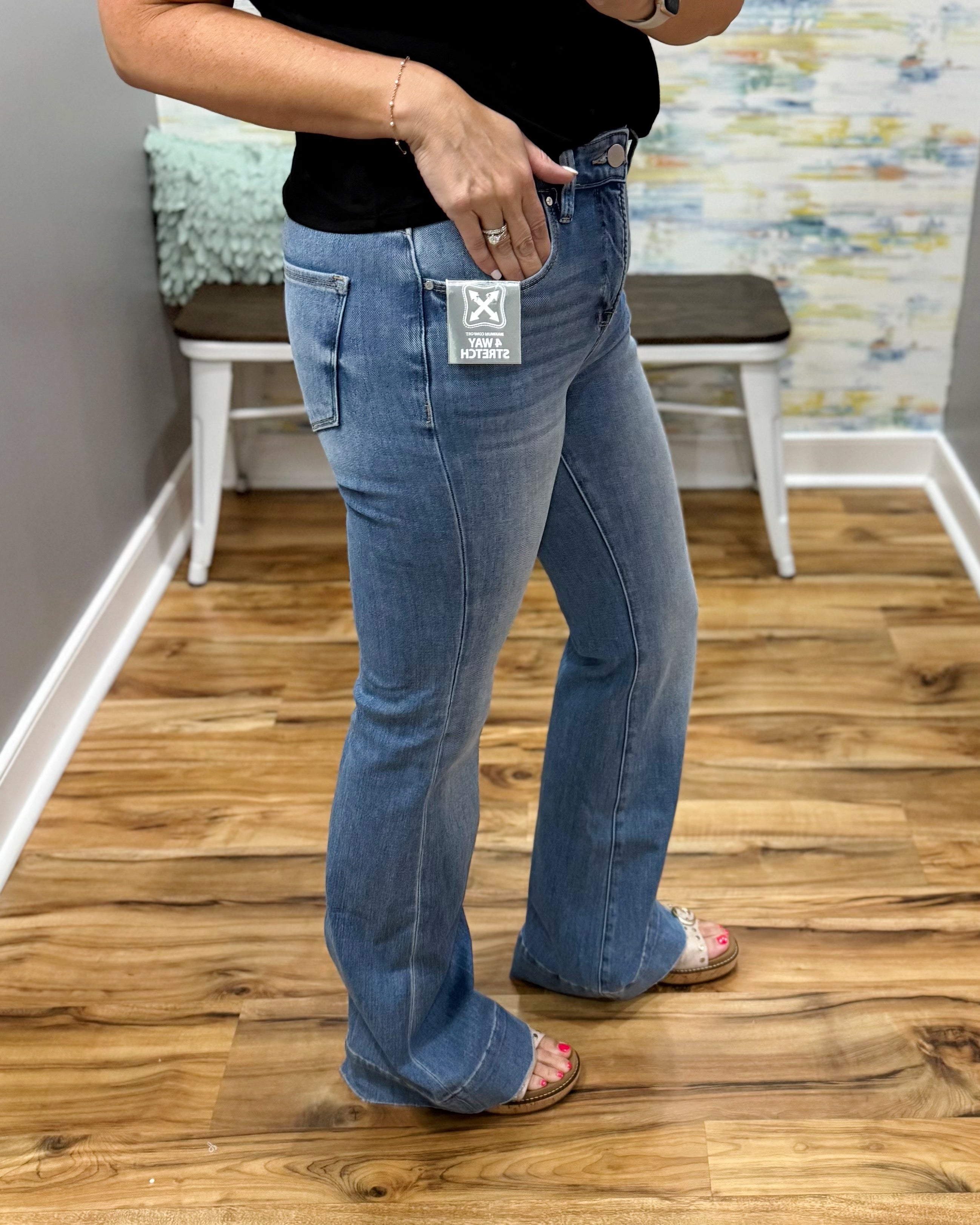 Person wearing blue jeans with a brand tag on a wooden floor.