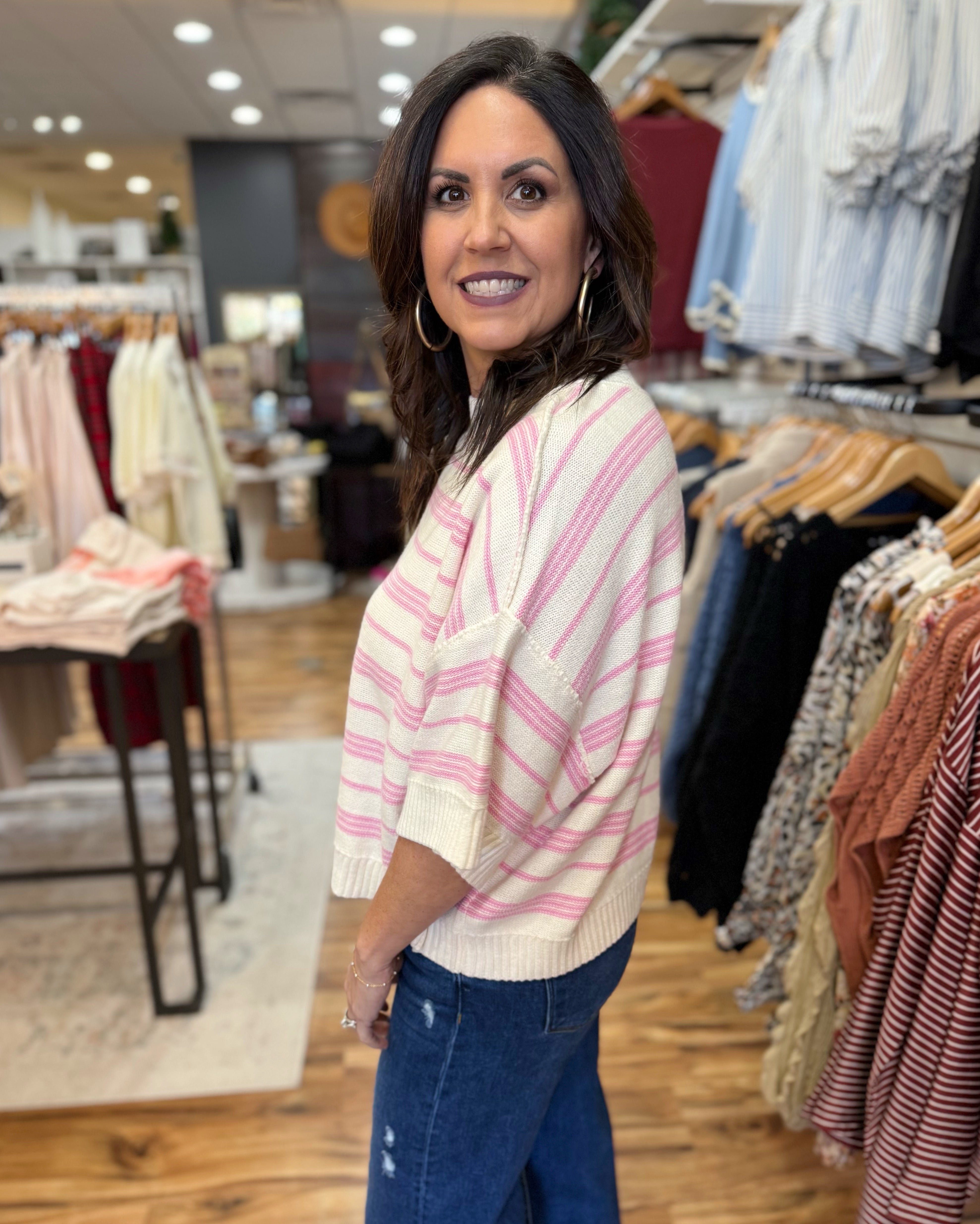 Woman standing in a clothing store with racks of clothes in the background