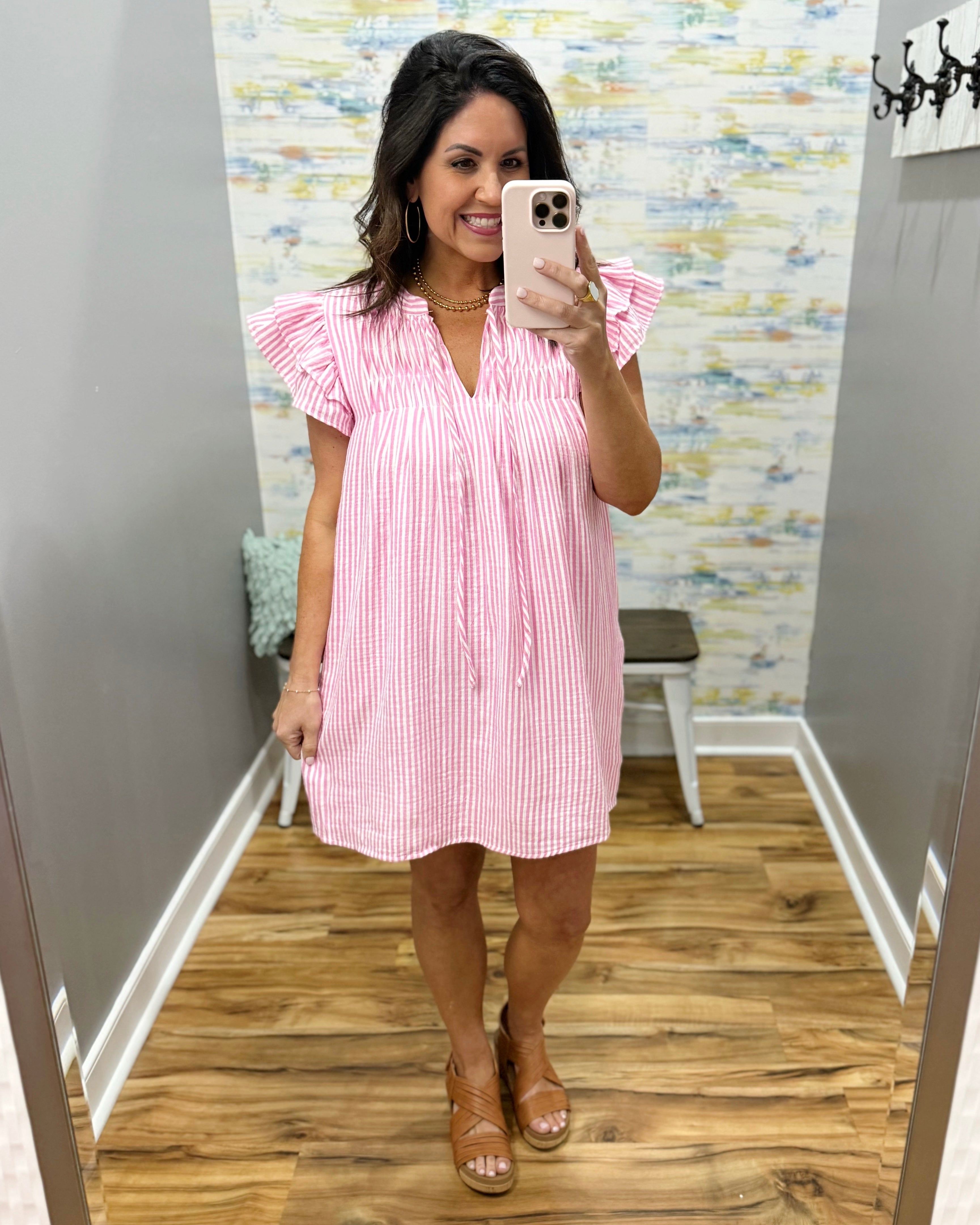 Woman taking a mirror selfie wearing a pink and white striped dress.