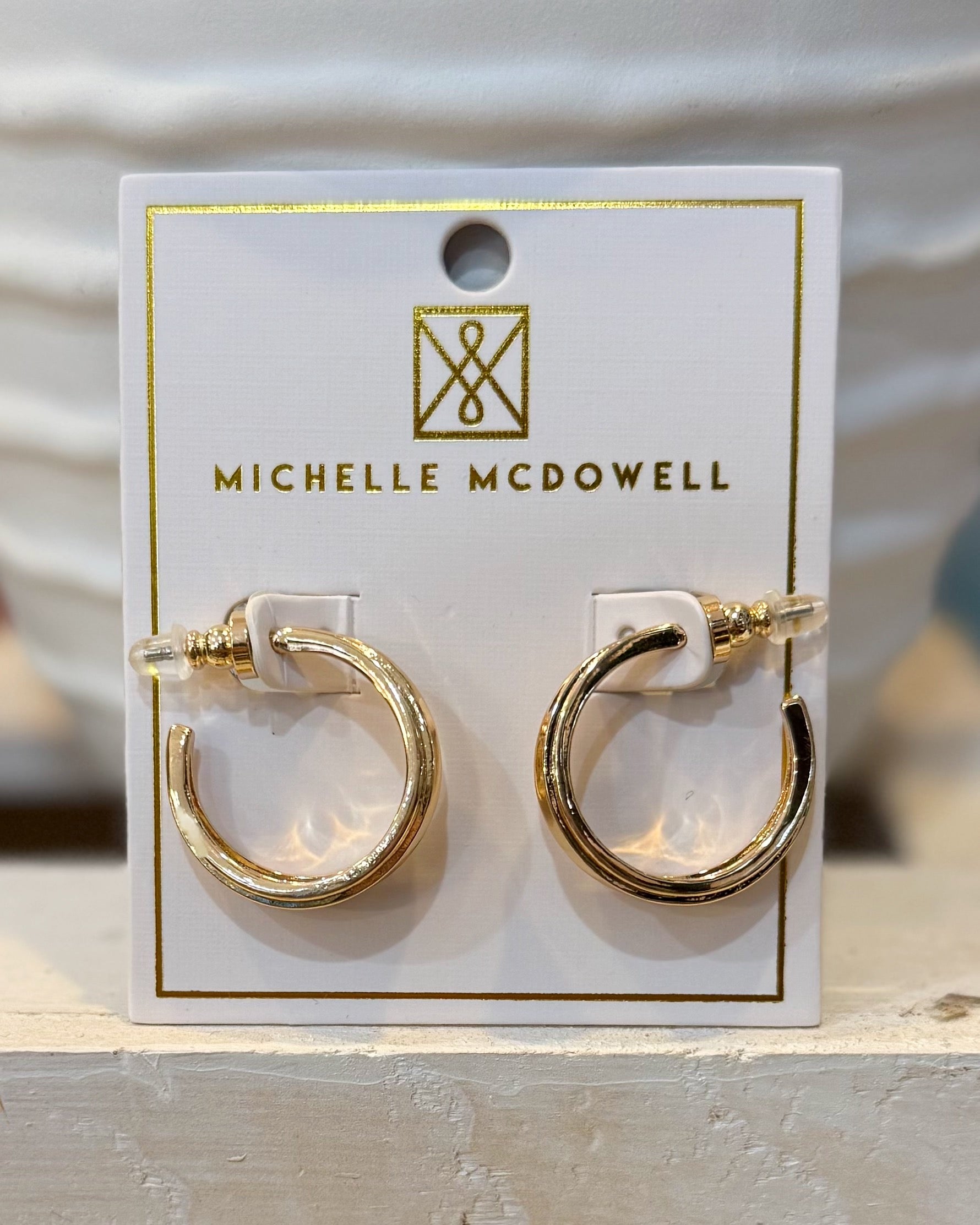Gold hoop earrings on a Michelle McDowell branded card.