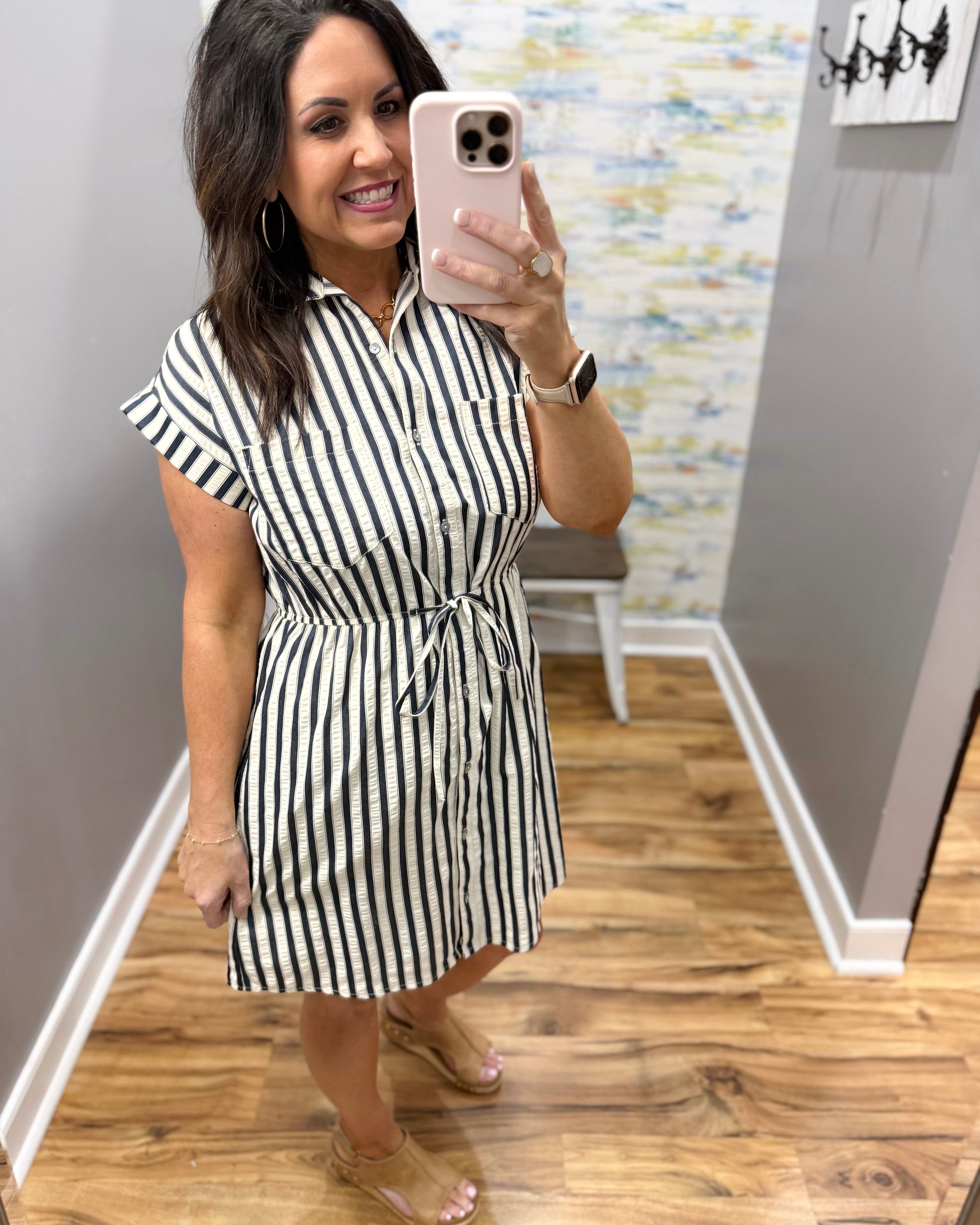 Woman wearing a black and white striped dress in a room with wooden flooring.