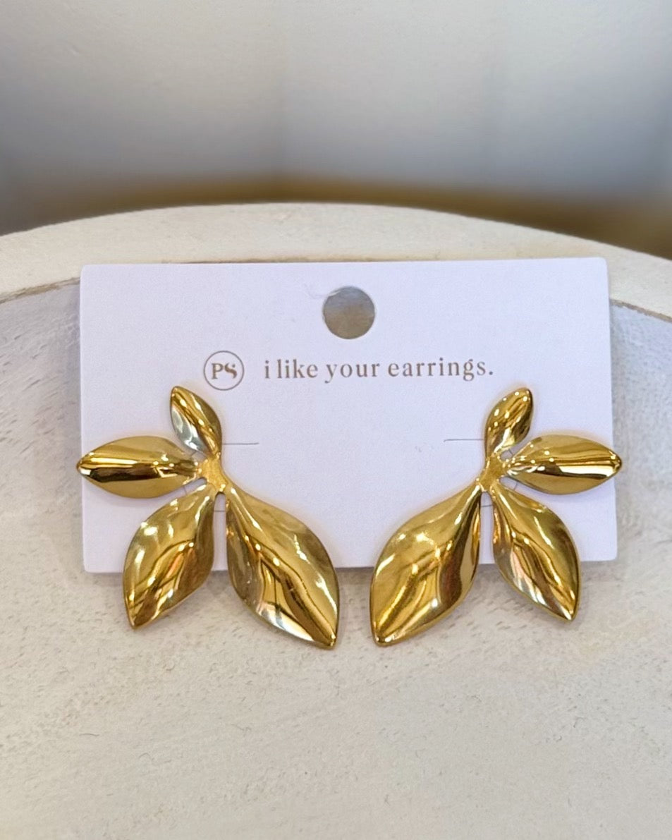 A pair of gold leaf-shaped stud earrings displayed on a white card that reads 'i like your earrings.' with a small 'pk' logo, set against a neutral cream background.