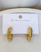 A pair of textured gold huggie hoop earrings displayed on a white card that reads 'i like your earrings.' with a small 'P4' logo, set against a neutral cream background.