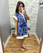 Woman taking a mirror selfie wearing a blue and white dress with a geometric pattern.