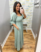 Woman wearing a light green dress in a room with a colorful wall.