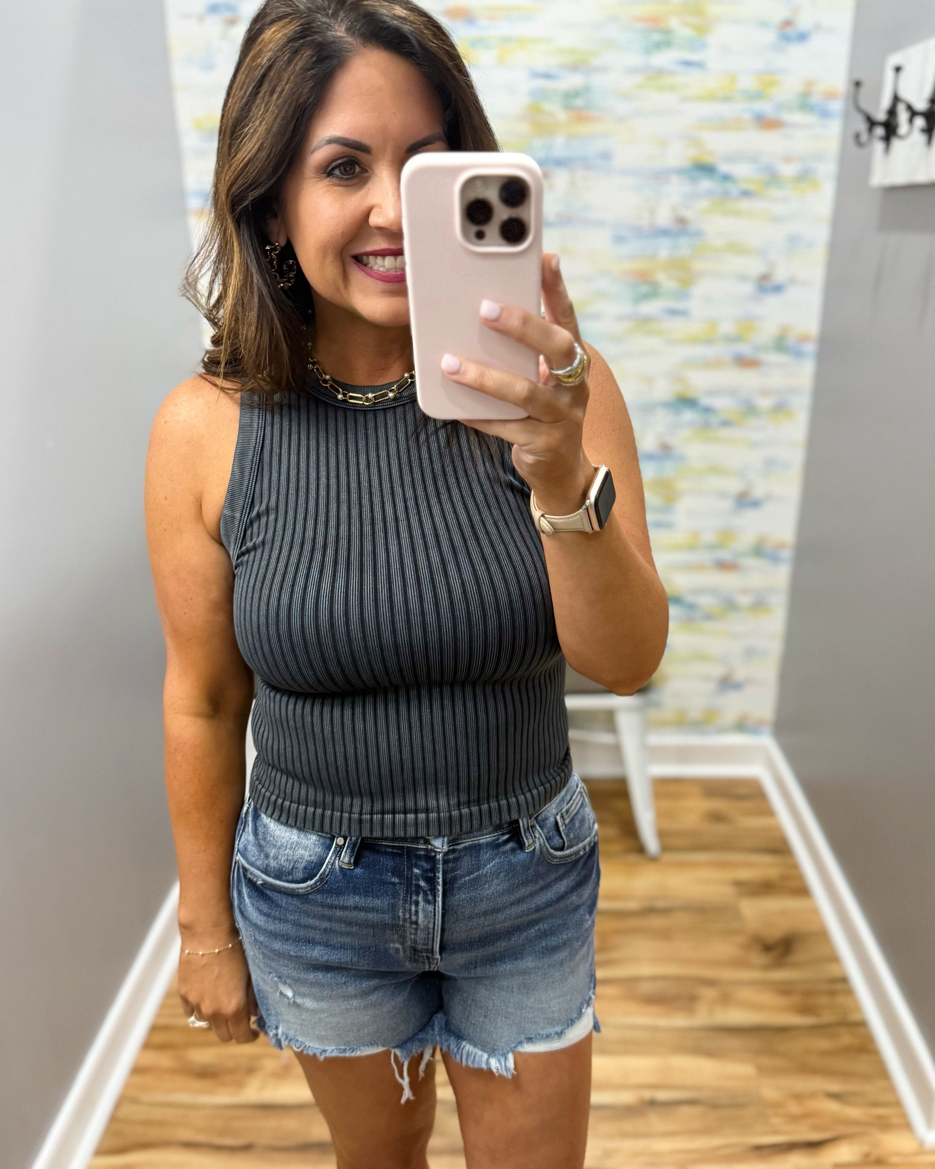 woman wearing black tank with denim shorts.