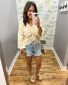 woman wearing a bell sleeve top in natural. 