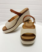 Pair of beige wedge sandals with brown straps on a white background