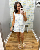 woman wearing a white top and shorts with blue palm trees embroidered on them.