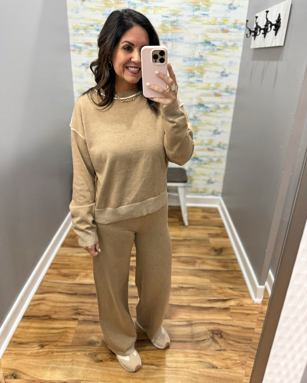 woman taking a selfie wearing a two-piece set in mocha with cream pipe stitching.  Set includes pants and long sleeve top.