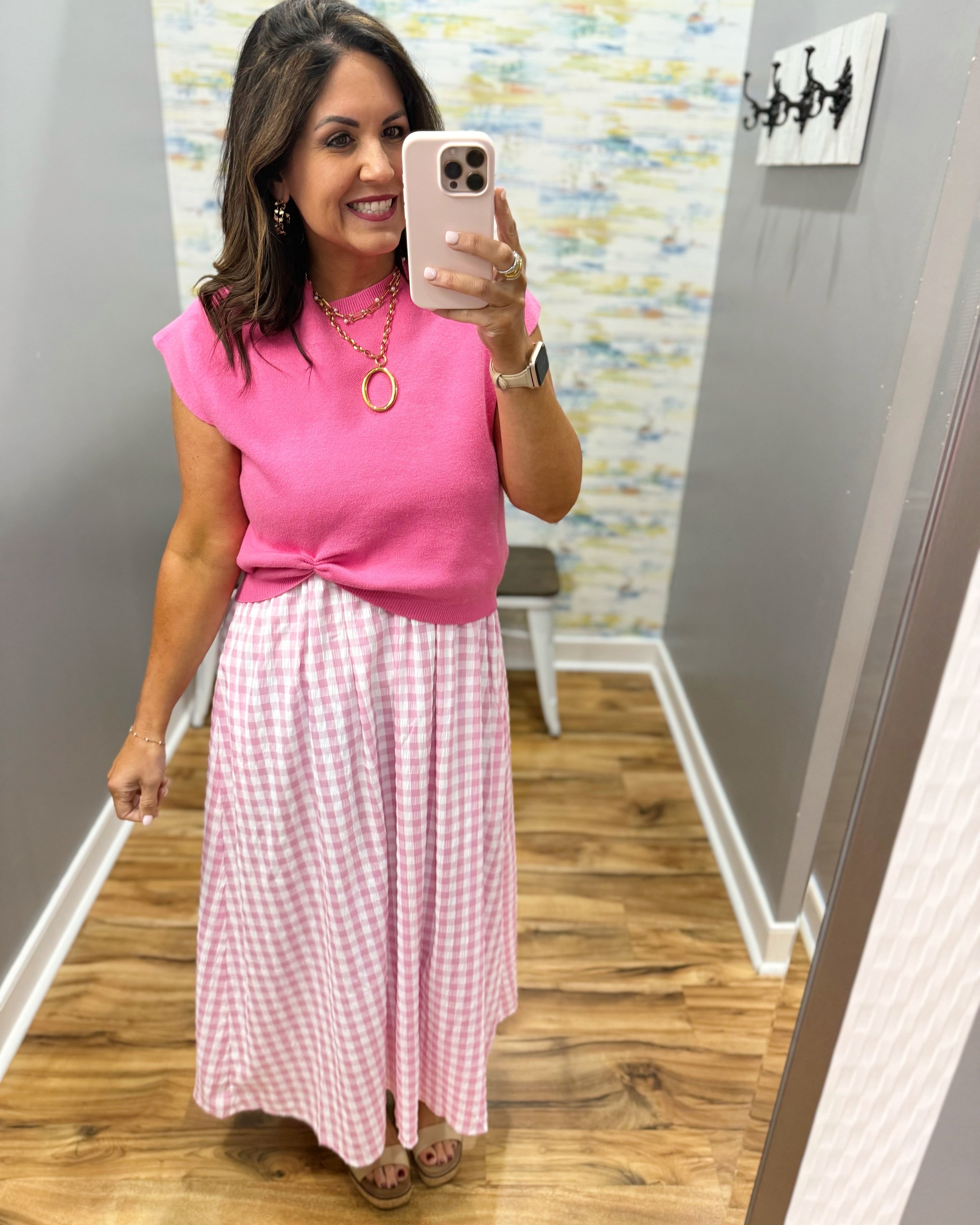 woman wearing gingham print dress in pink with pink sweater over top.