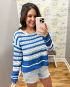 Woman wearing a blue and white striped sweater taking a mirror selfie.