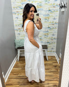 Woman wearing a white dress in a room with a textured wall.